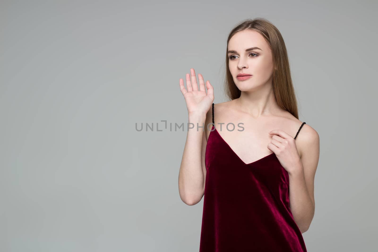 Portrait of posing young model long-haired blond girl in dark red dress showing emotions