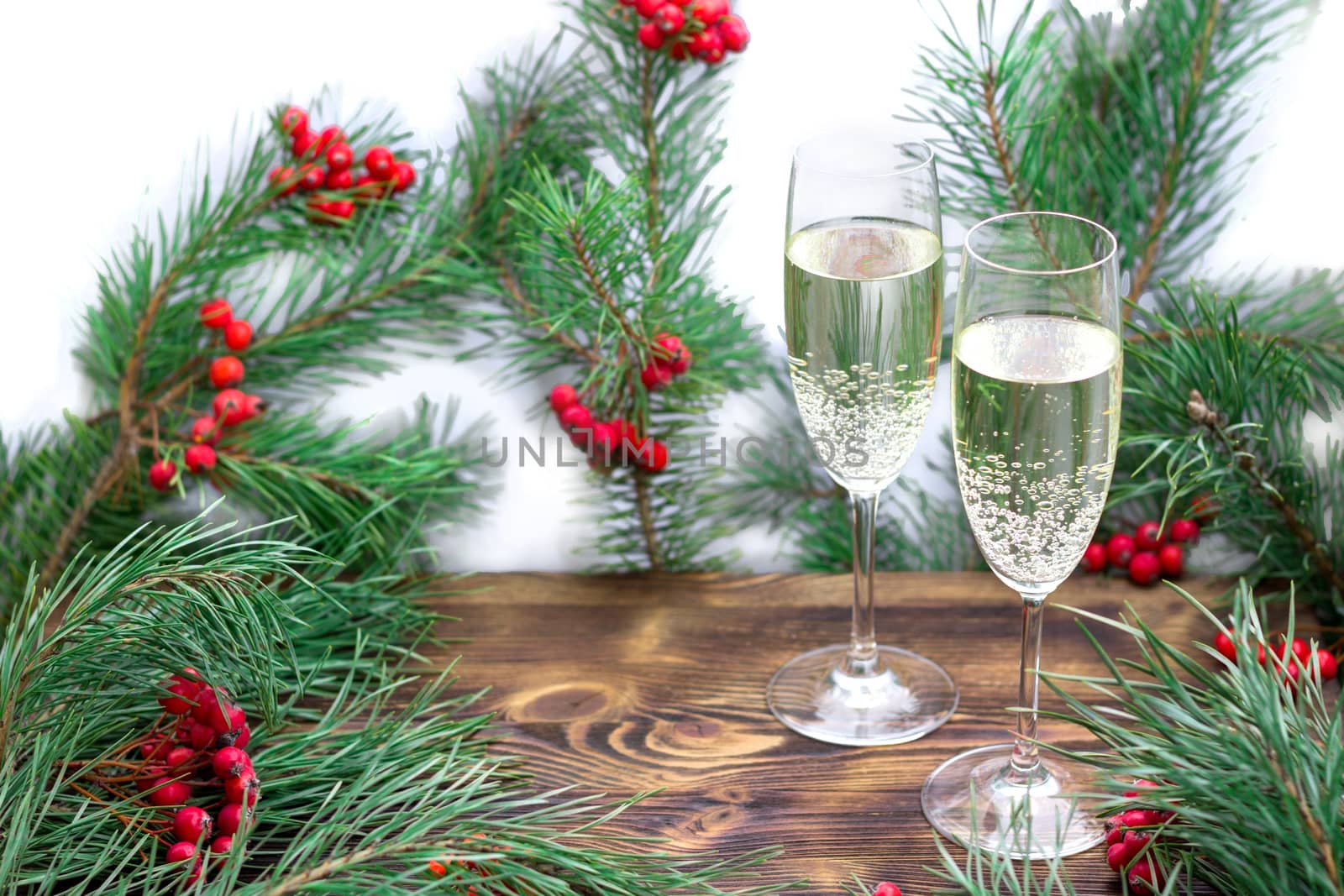 Christmas and New Year seasonal composition with pine tree branches, two glasses of champaign and red rowan berries