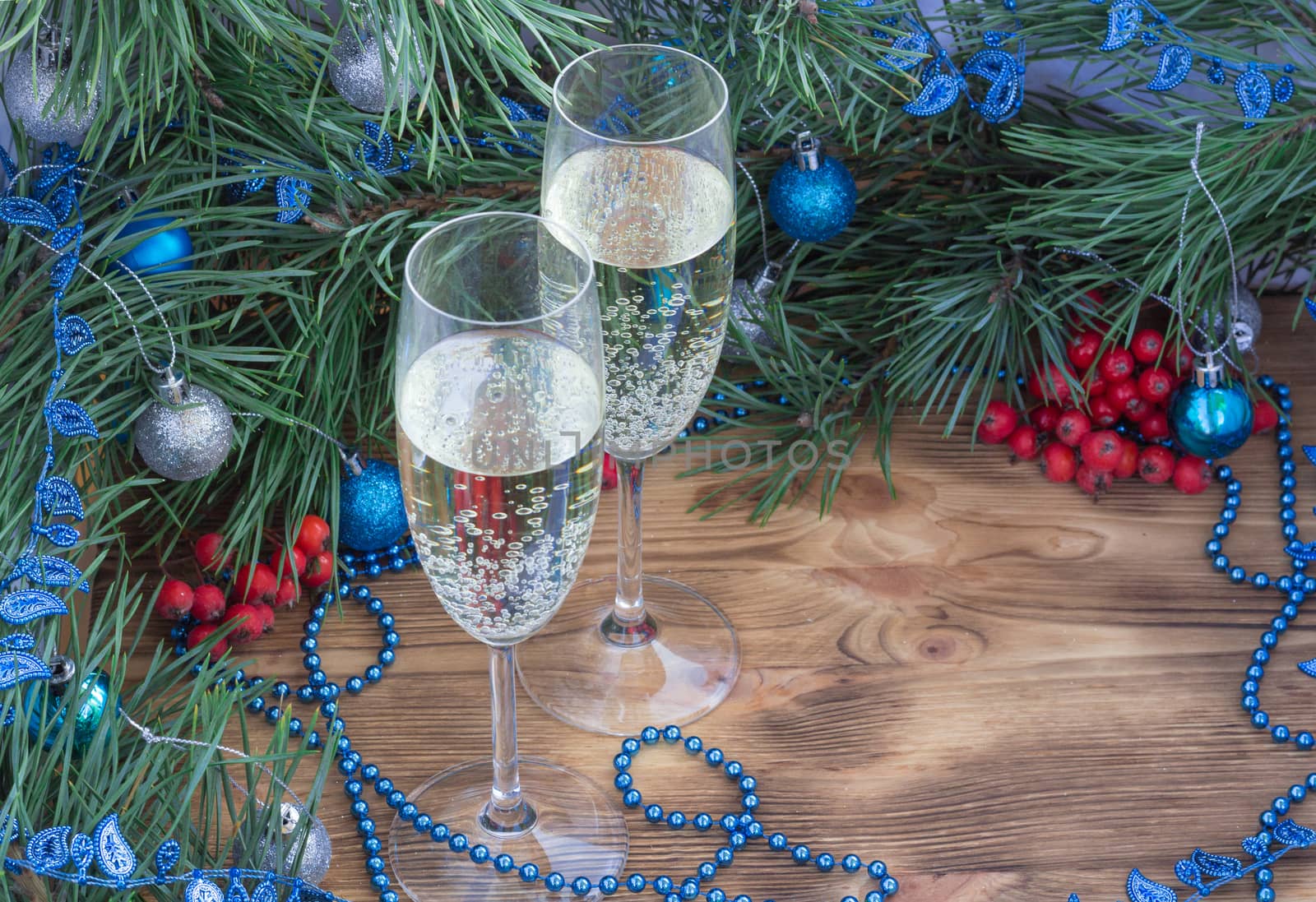 Christmas and New Year still life composition with two champaign glasses, pine tree acerose, red rowan berries, blue and silver balls, garland ornament decoration, copy space