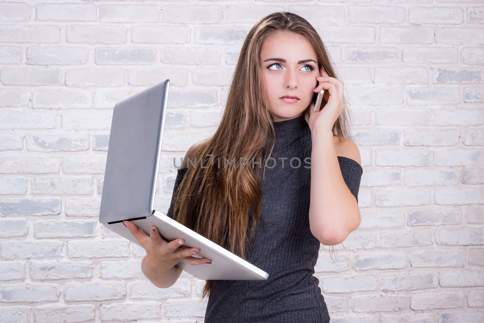 Young beautiful girl model with long hair imitates business lady, office manager or administrator with notebook and telephone