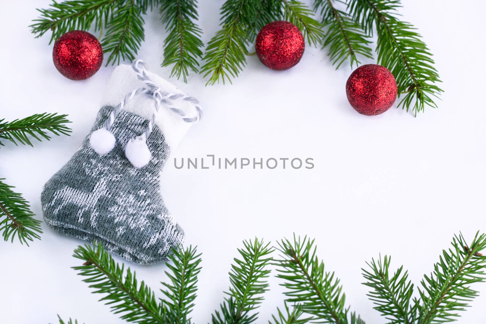 Gray Christmas stocking sock and red decoration balls on white background, frame of green fir tree branches