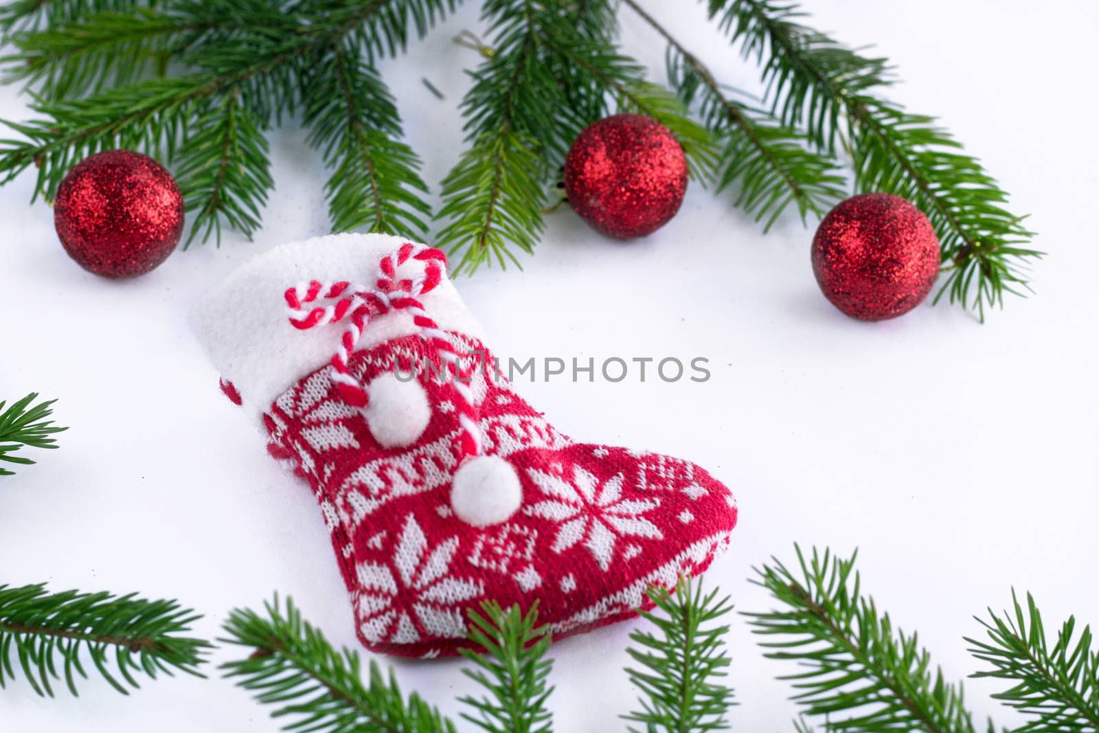 Red Christmas stocking sock and decoration balls on white background, green contiferous fir tree branches