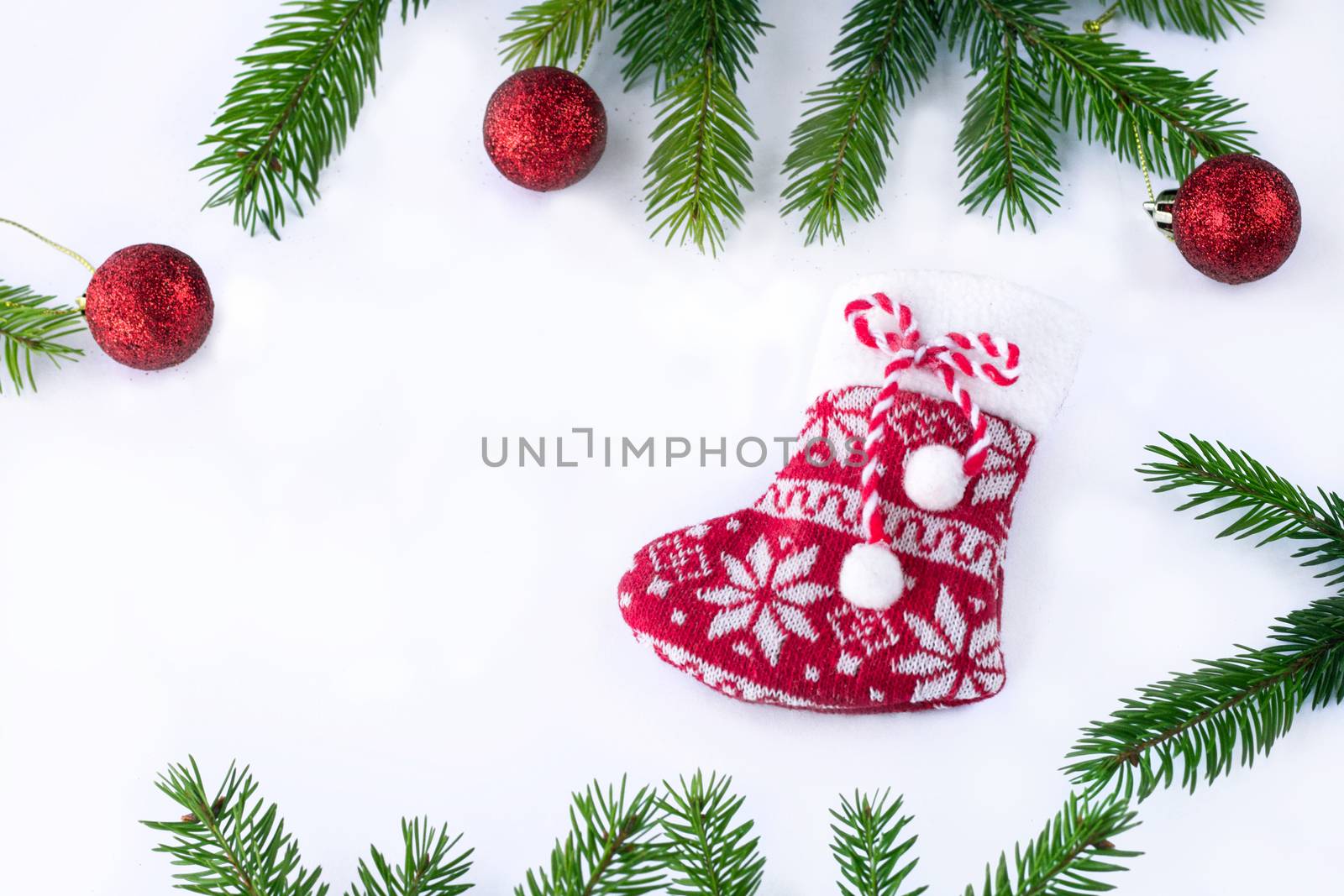 Red Christmas stocking sock and decoration balls on white background, frame of green contiferous tree branches