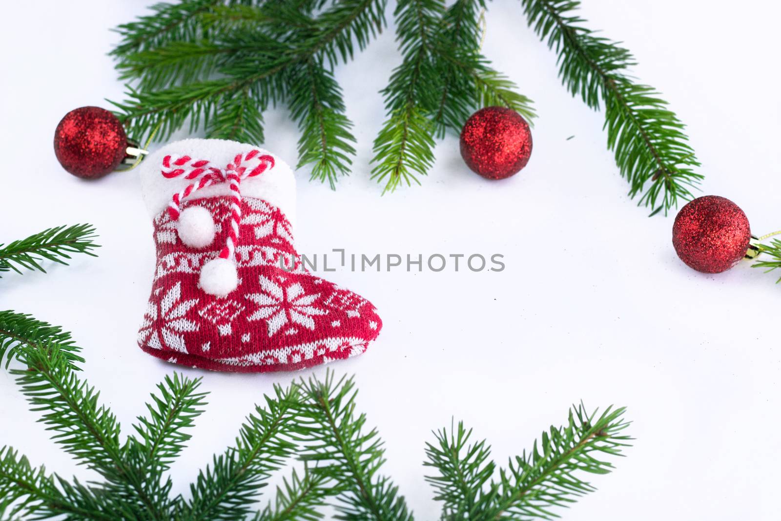 Red Christmas stocking sock and decoration balls on white background, frame of green fir tree branches