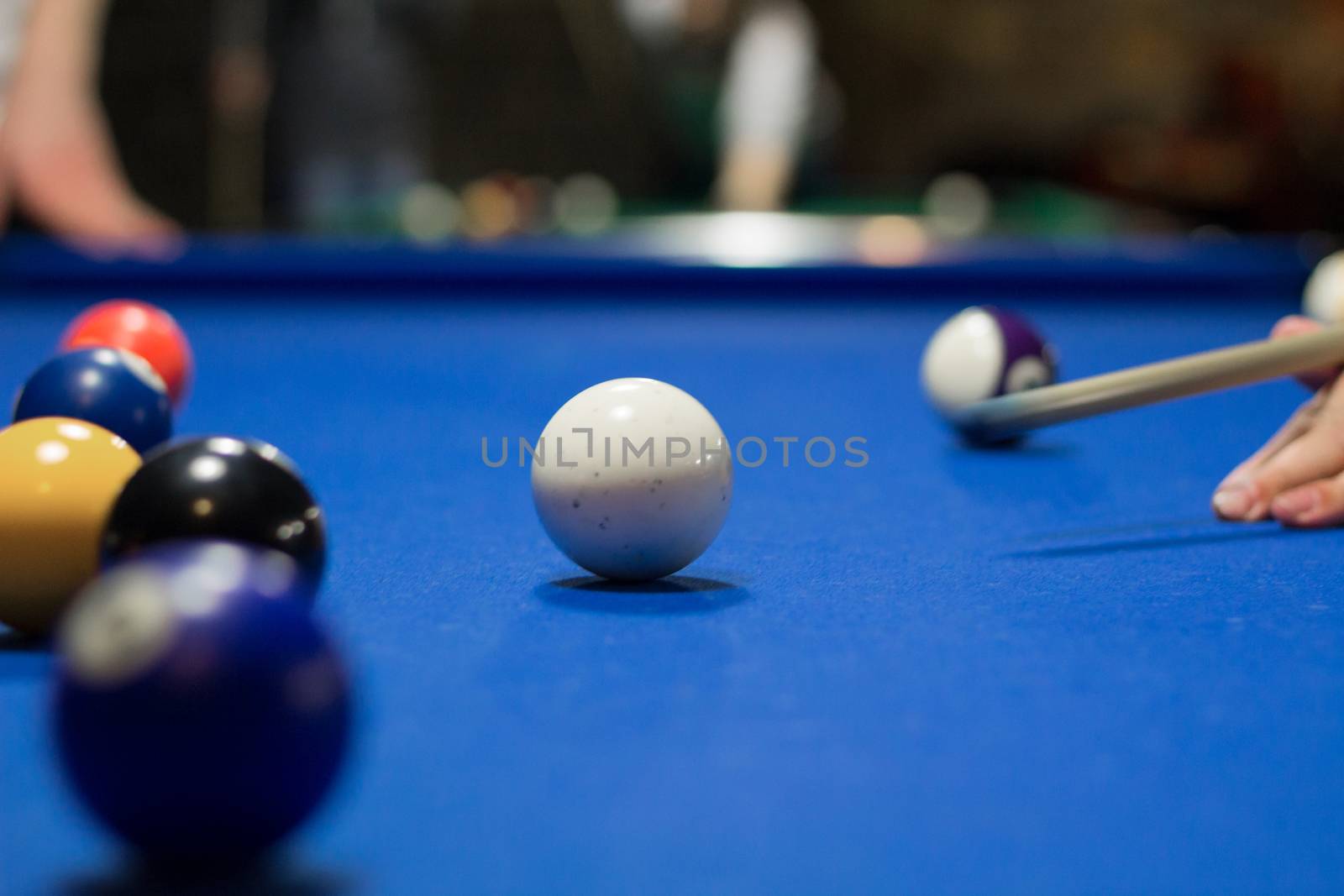 Billiard pool game in progress, player aims to shoot balls with cue