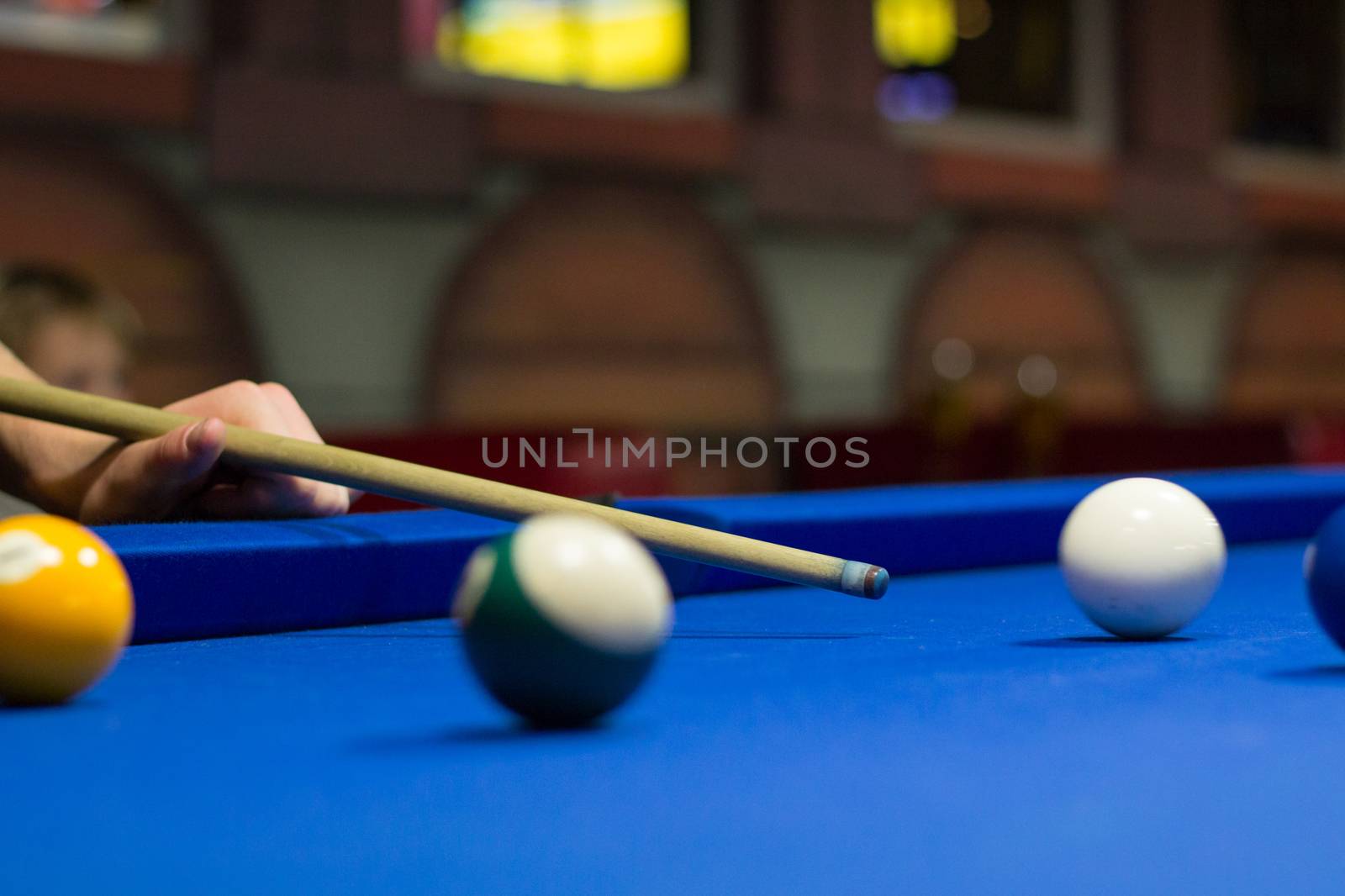 Billiard pool game in progress, player aims to shoot balls with cue