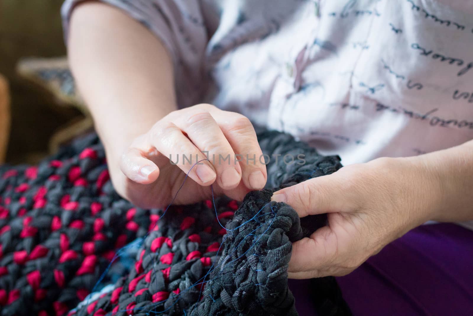 Elderly woman hands doing sewing work with needle and thread by VeraVerano