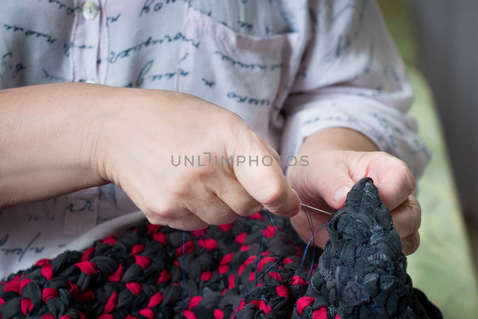 Close-up of elderly lady doing sewing hand work with needle and thread