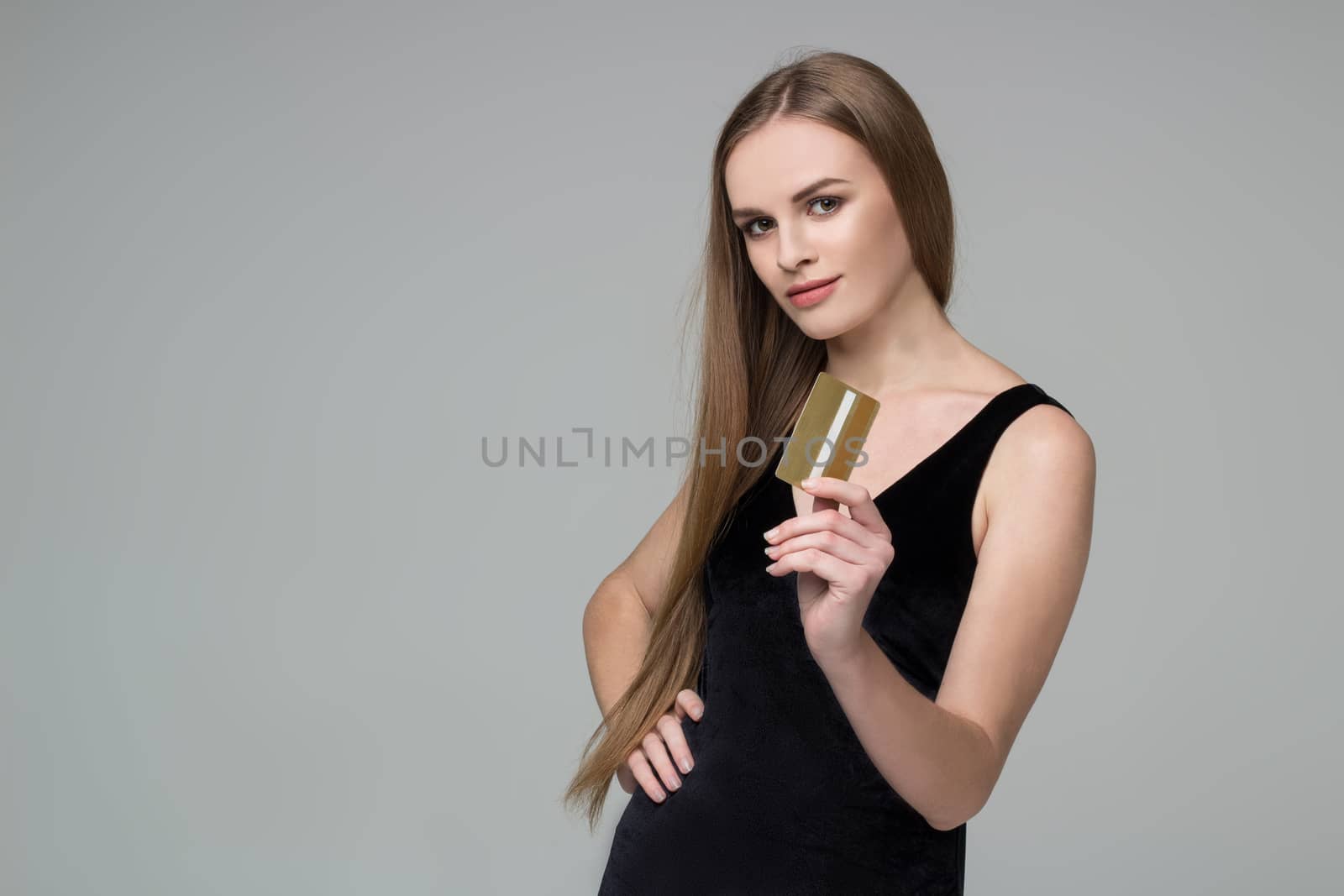 Blond girl in black holds golden banking card shopping payment by VeraVerano