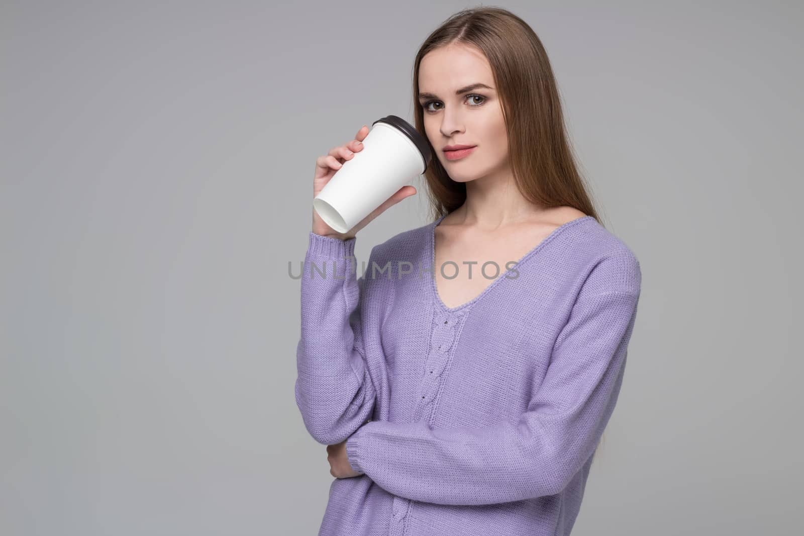 Girl in lilac jamper drinking coffee from paper plastic glass by VeraVerano