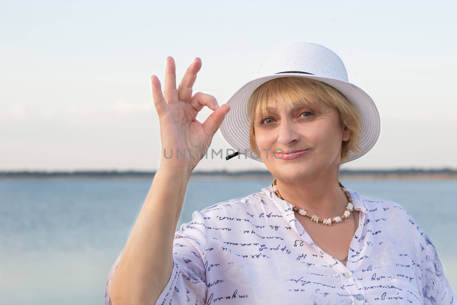 Happy retired lady woman in white hat shows okey geste by VeraVerano