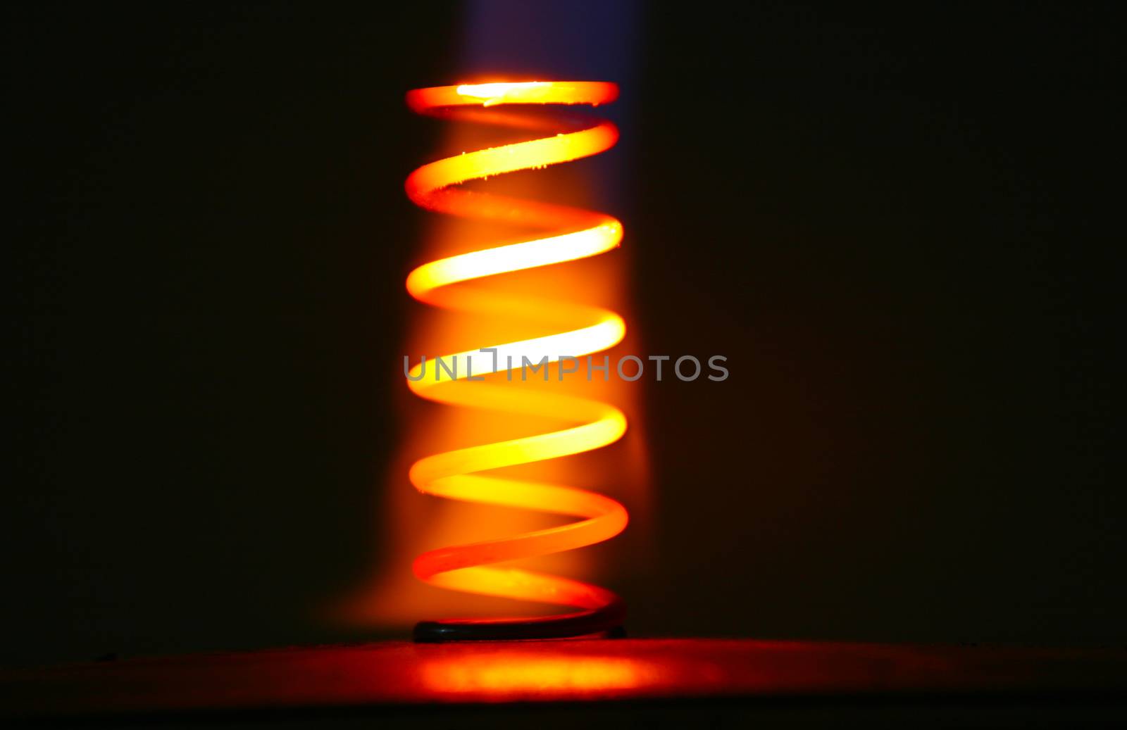 Piece of metal heated by the flame of gas torch. Glowing red and yellow in the dark.
