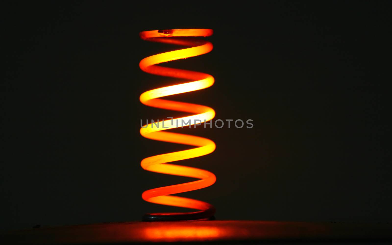 Red hot coil spring glowing in the dark.