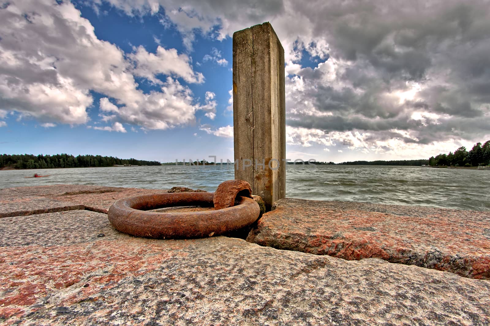 Stone boat dock by the sea with wooden pole.