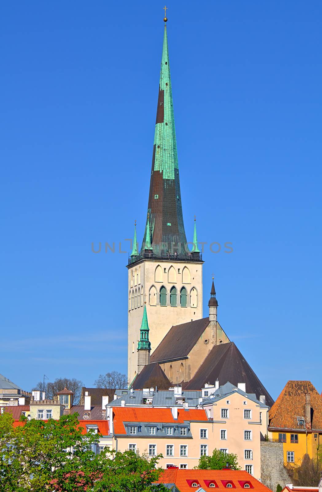 St. Olaf's church in Tallinn, Estonia. Sharp tower of the church with calm blue summer sky on the background. Some colorful buildings in the foreground.