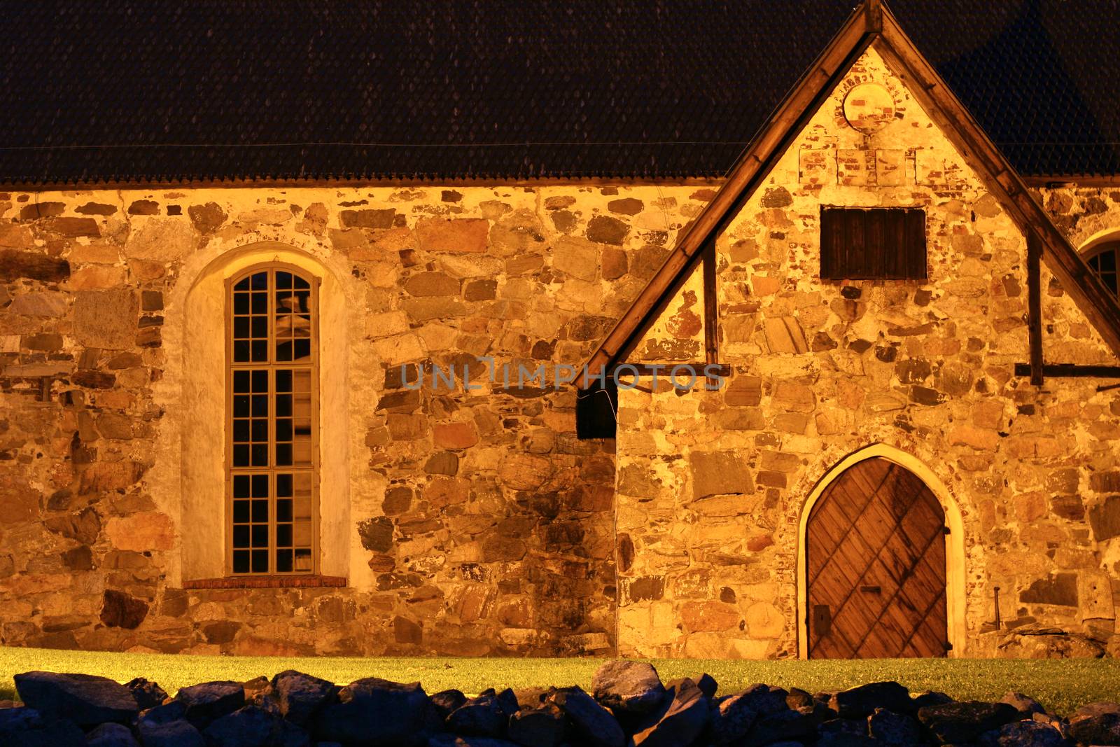 Lighted stone wall of an old church. Photo taken at night in the dark.