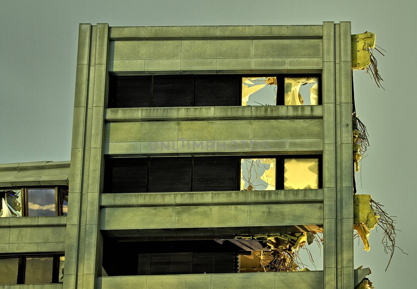 Only one wall of destroyed building still standing. Dramatic low light photo of a high wall with broken windows and cables hanging out.