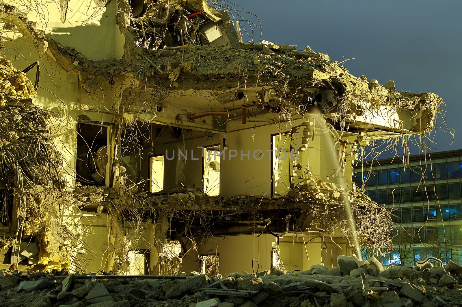 Heavily damaged concrete building after disaster. Half of the building still standing while other half has collapsed exposing the interior of the house.