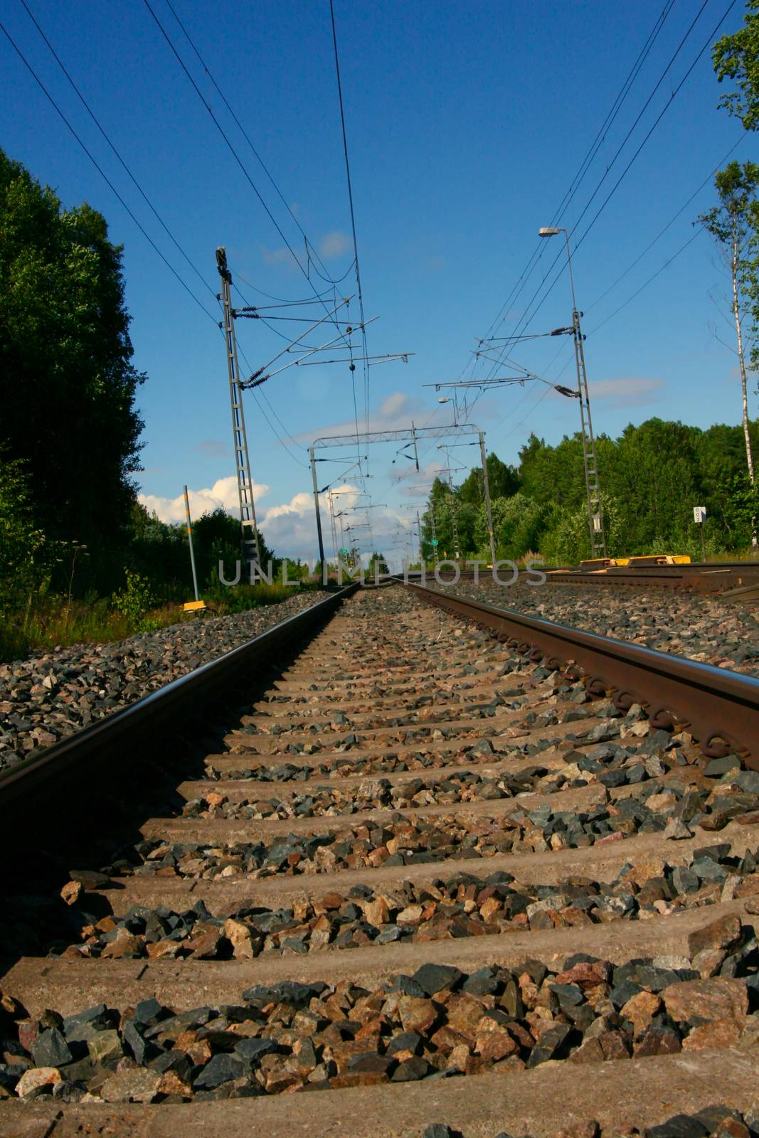 Tilted view of empty railway. Power lines hanging above.