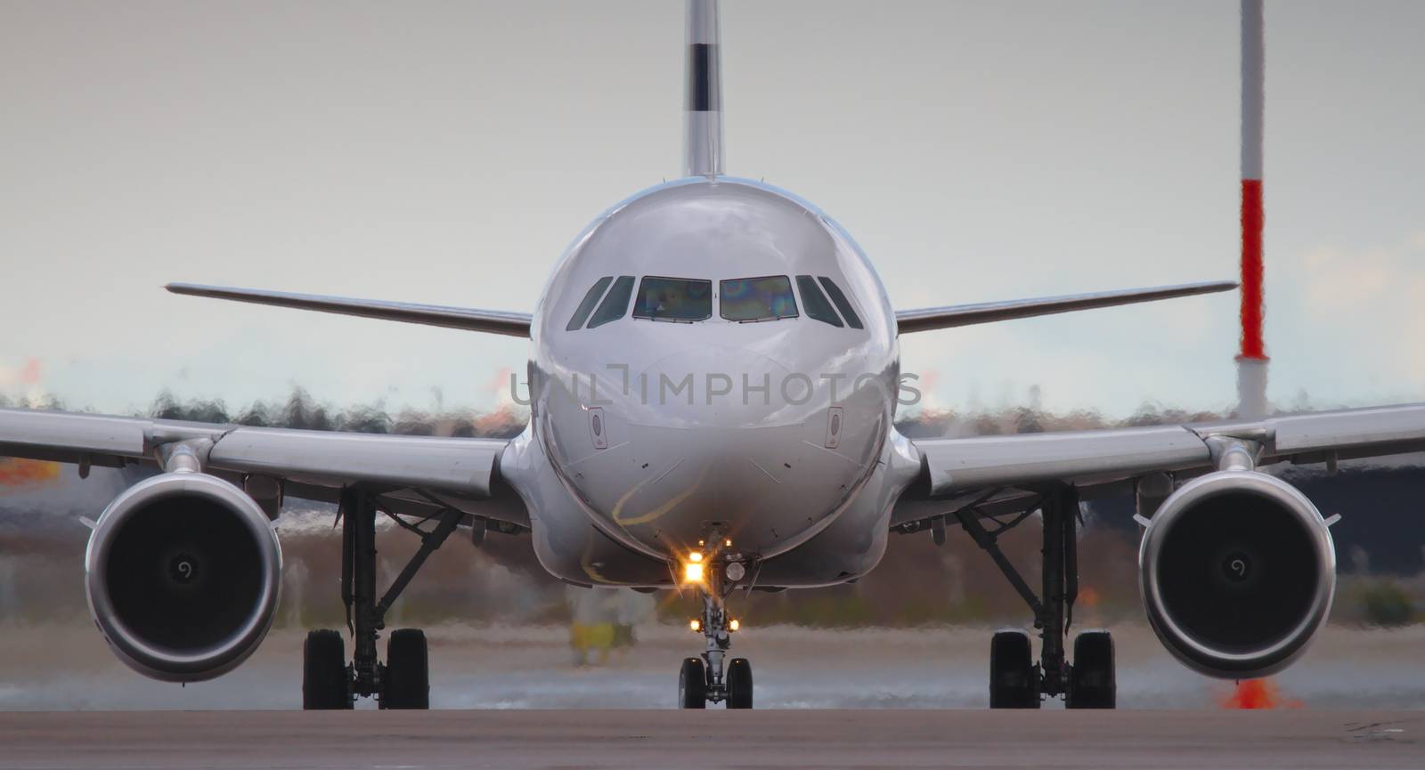 Closeup of a nose and two jet engines of a white passenger airplane standing on the runway and waiting for permission to takeoff.