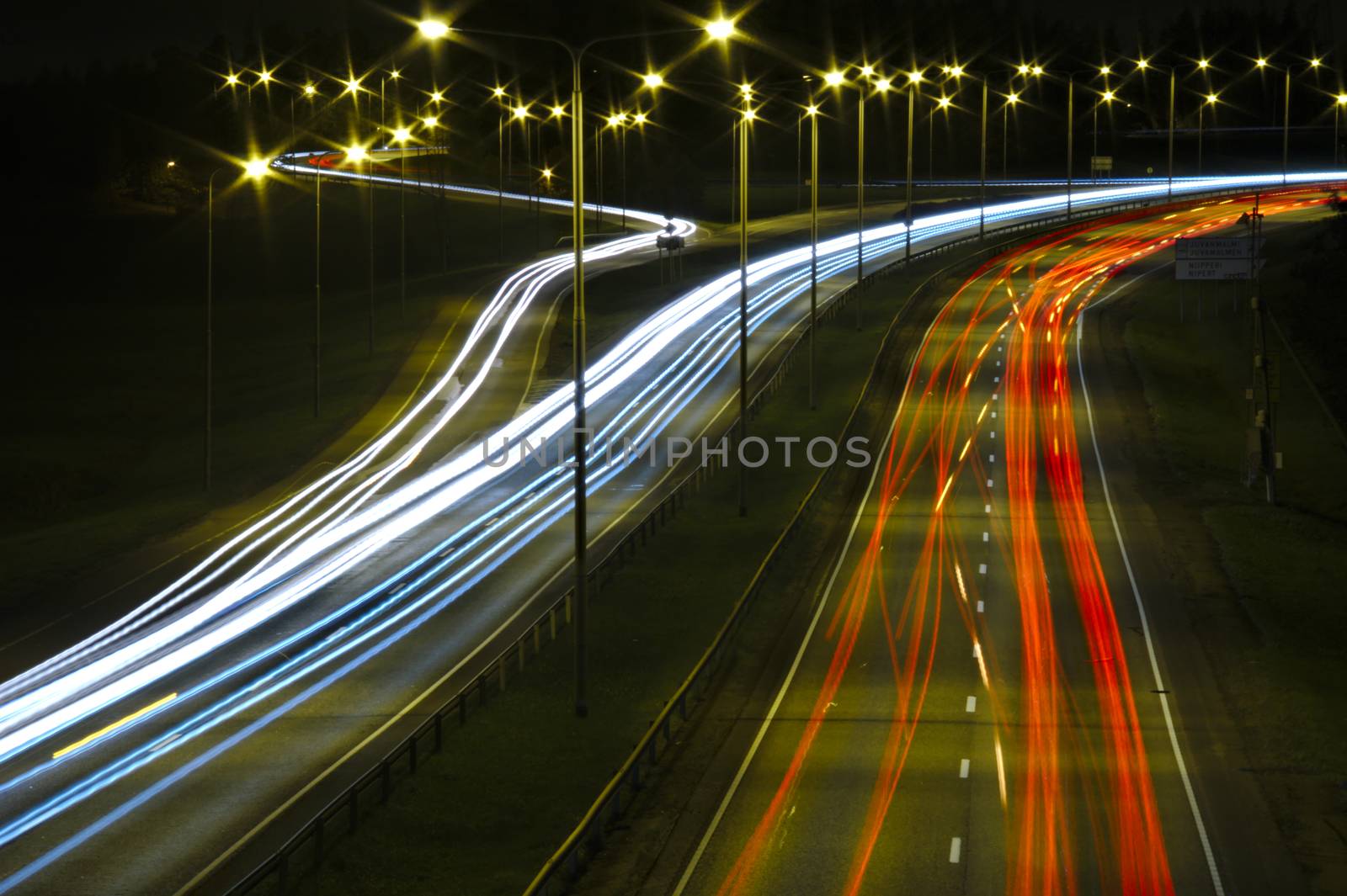 Red and white light trails of cars on a highway at night.