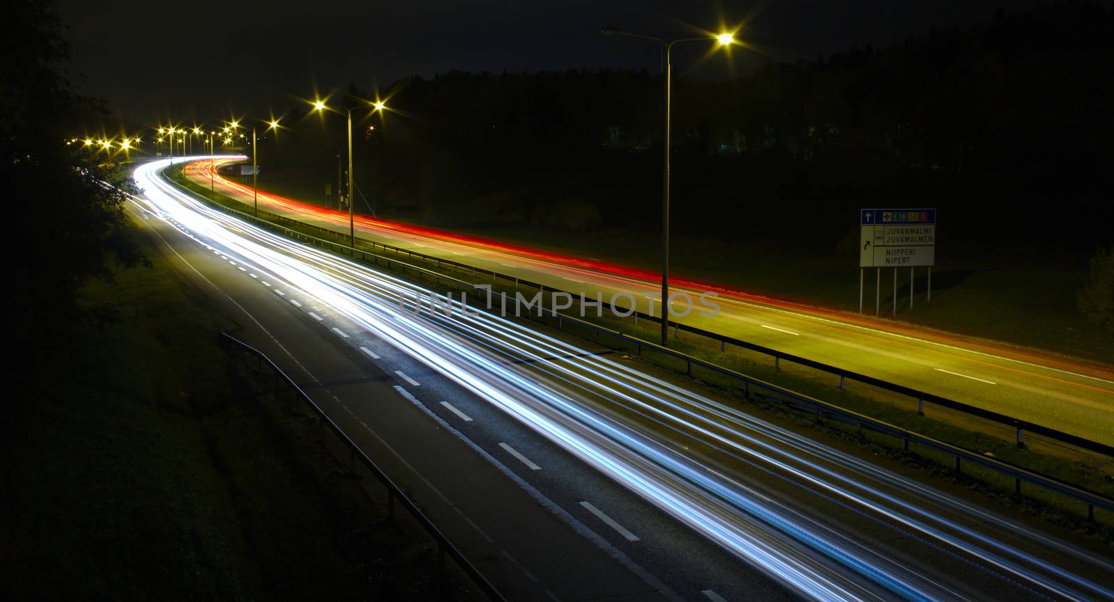 Fast traffic at night on busy motorway. Long exposure photo of cars leaving light trails.