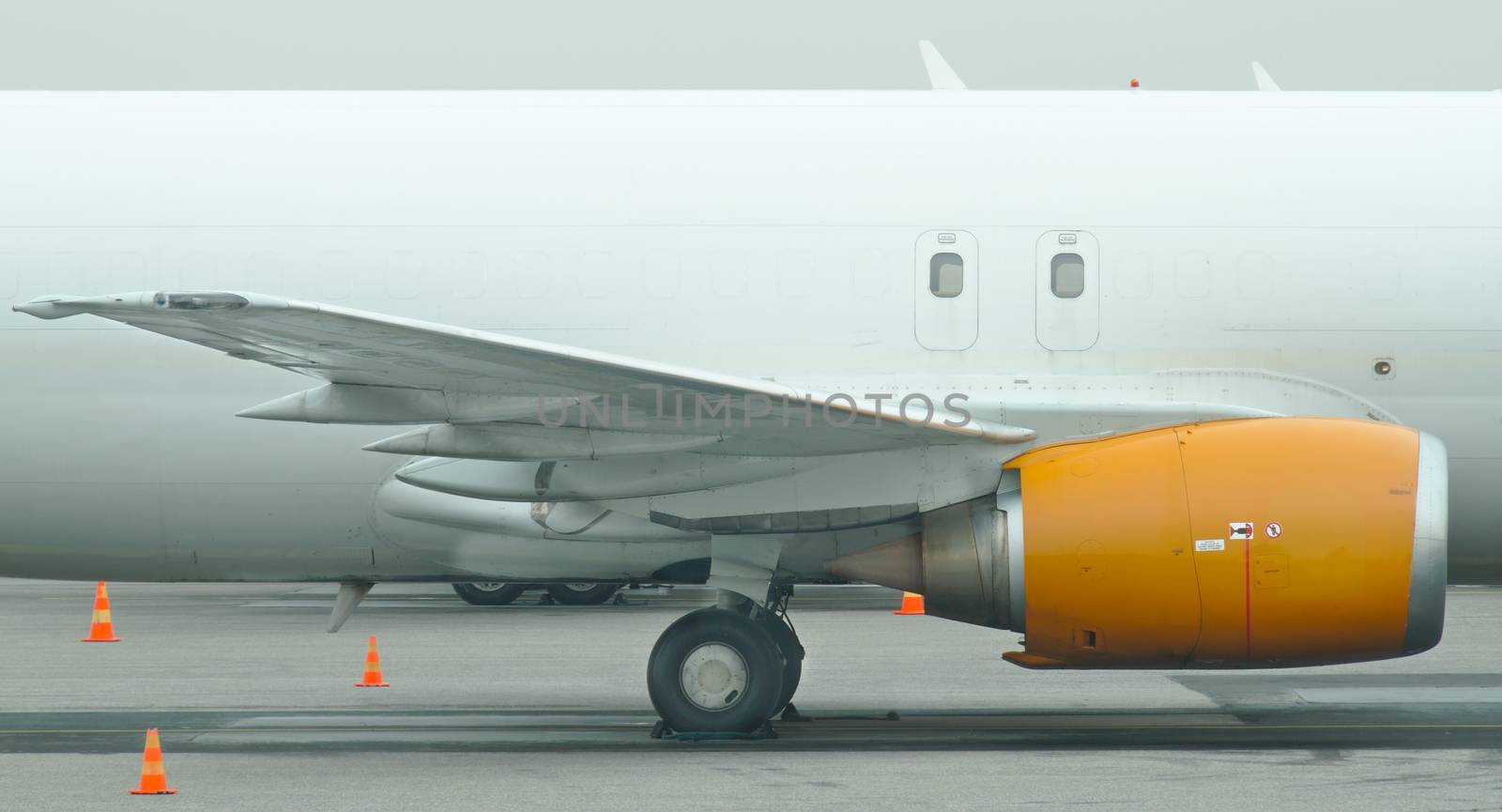 Yellow jet engine on a wing of white cargo plane. by Valokuva24