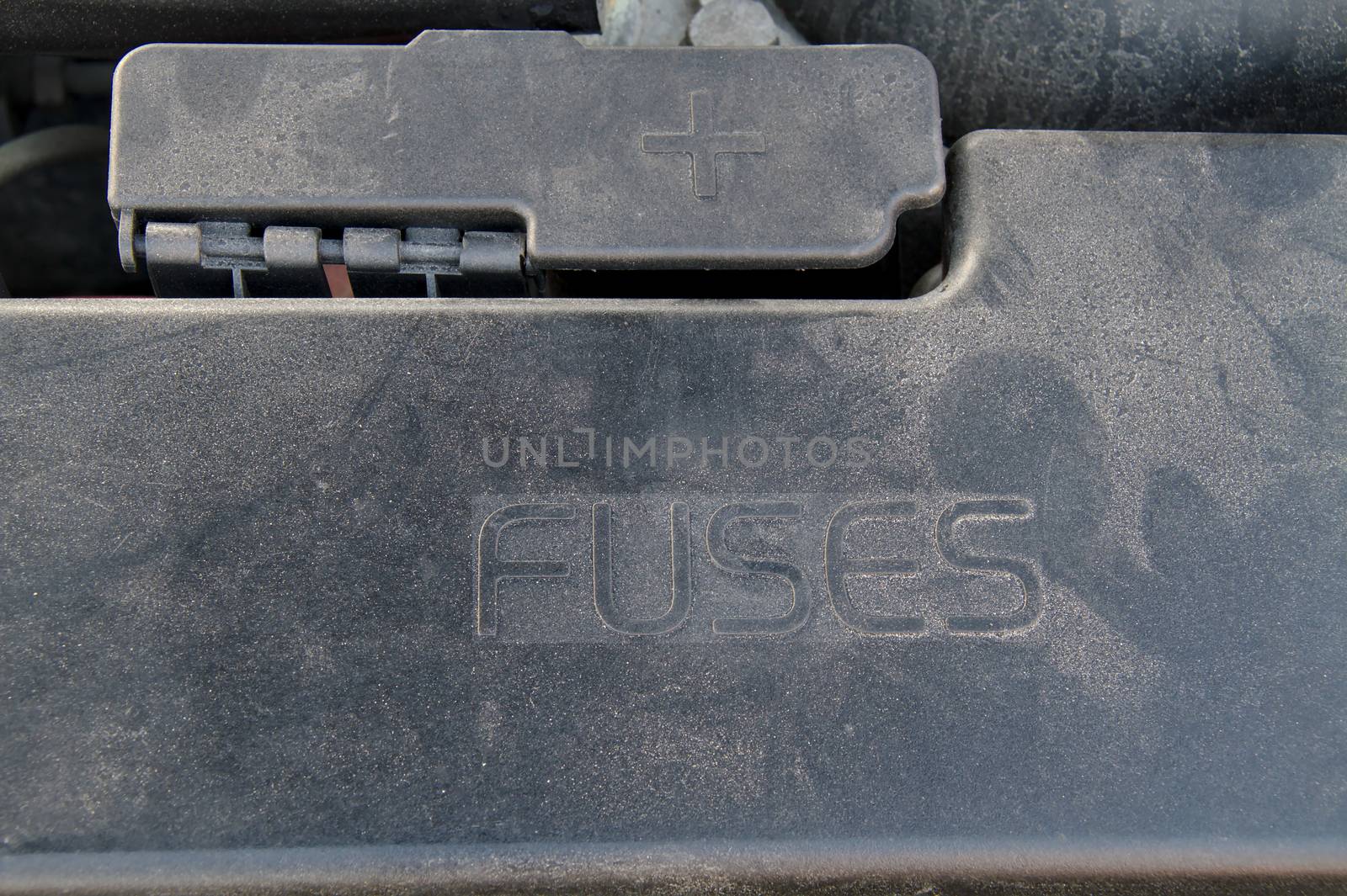 Cover of a under hood fuse box of a car. External plus terminal for jumper cables next to the fusebox.