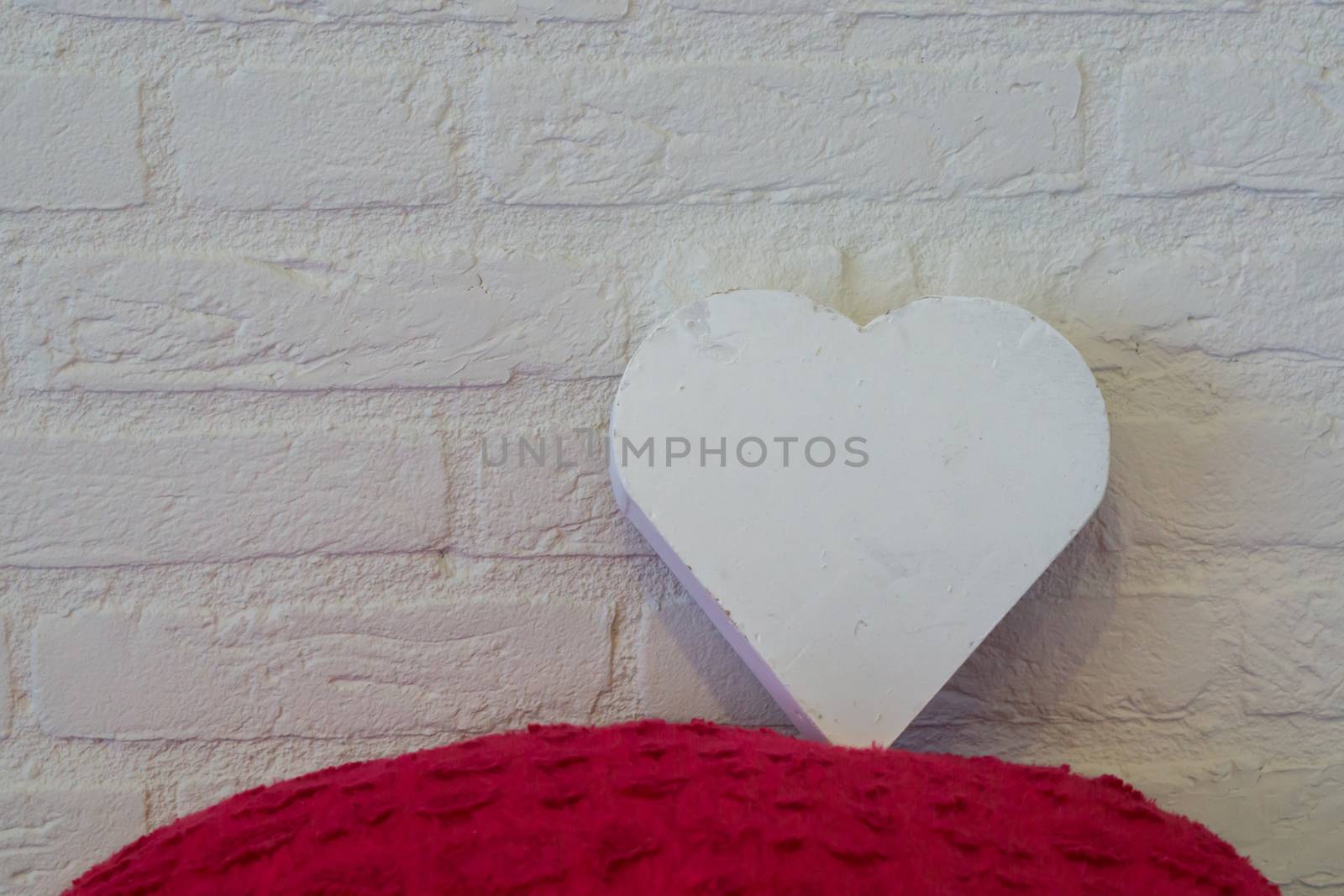 valentines day surprise concept, a brick wall decorated with a red pillow and a white wooden heart