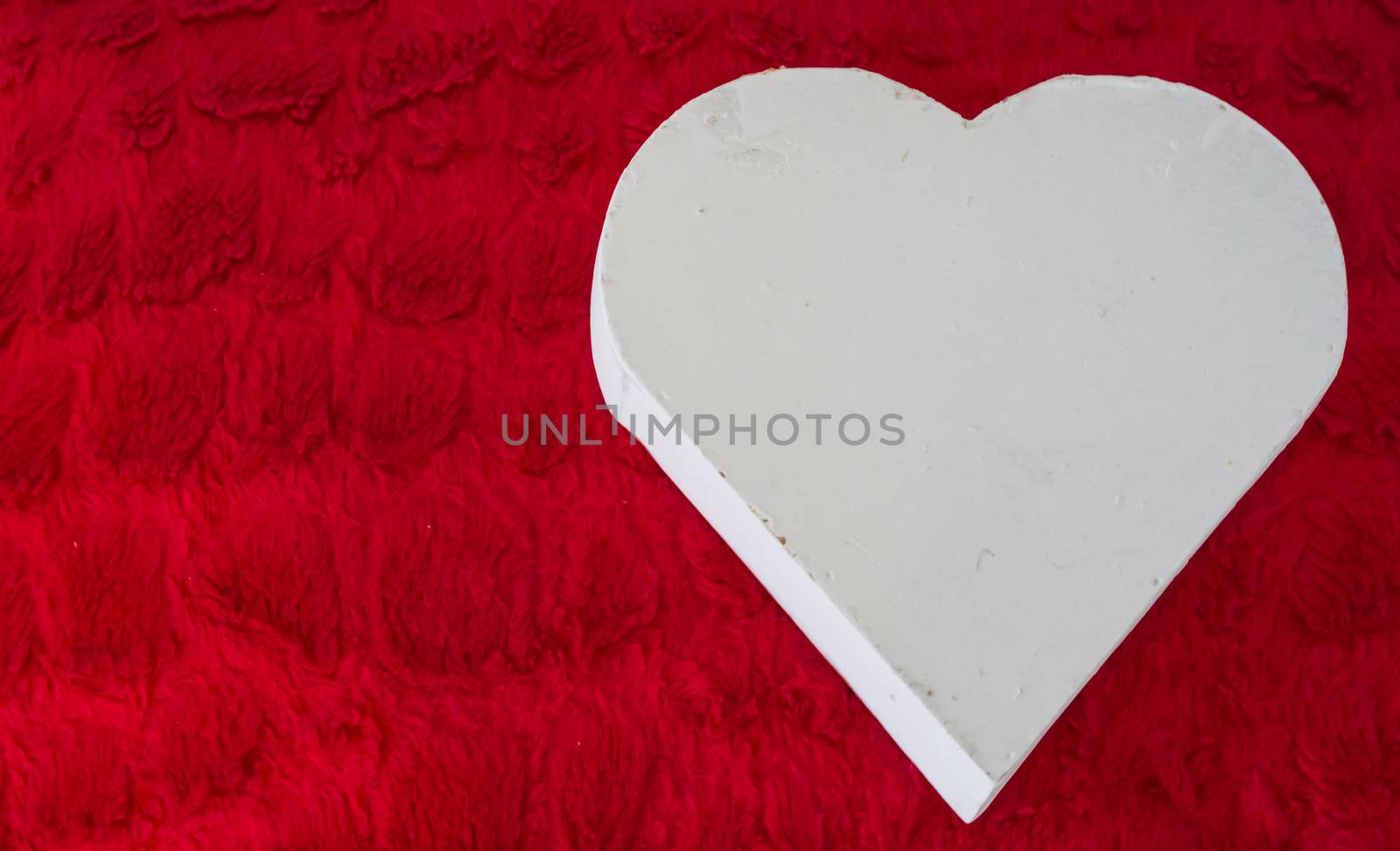 Valentines day background a white wooden heart laying on a red pillow by charlottebleijenberg