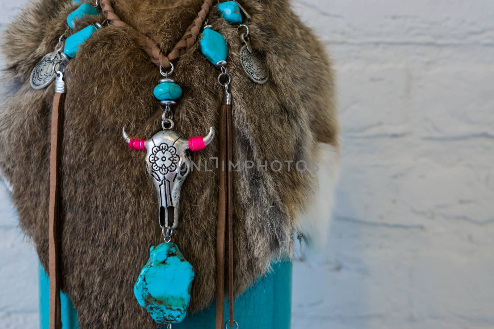 Native american background of animal fur decorated with a necklace with stones and a cow skull by charlottebleijenberg