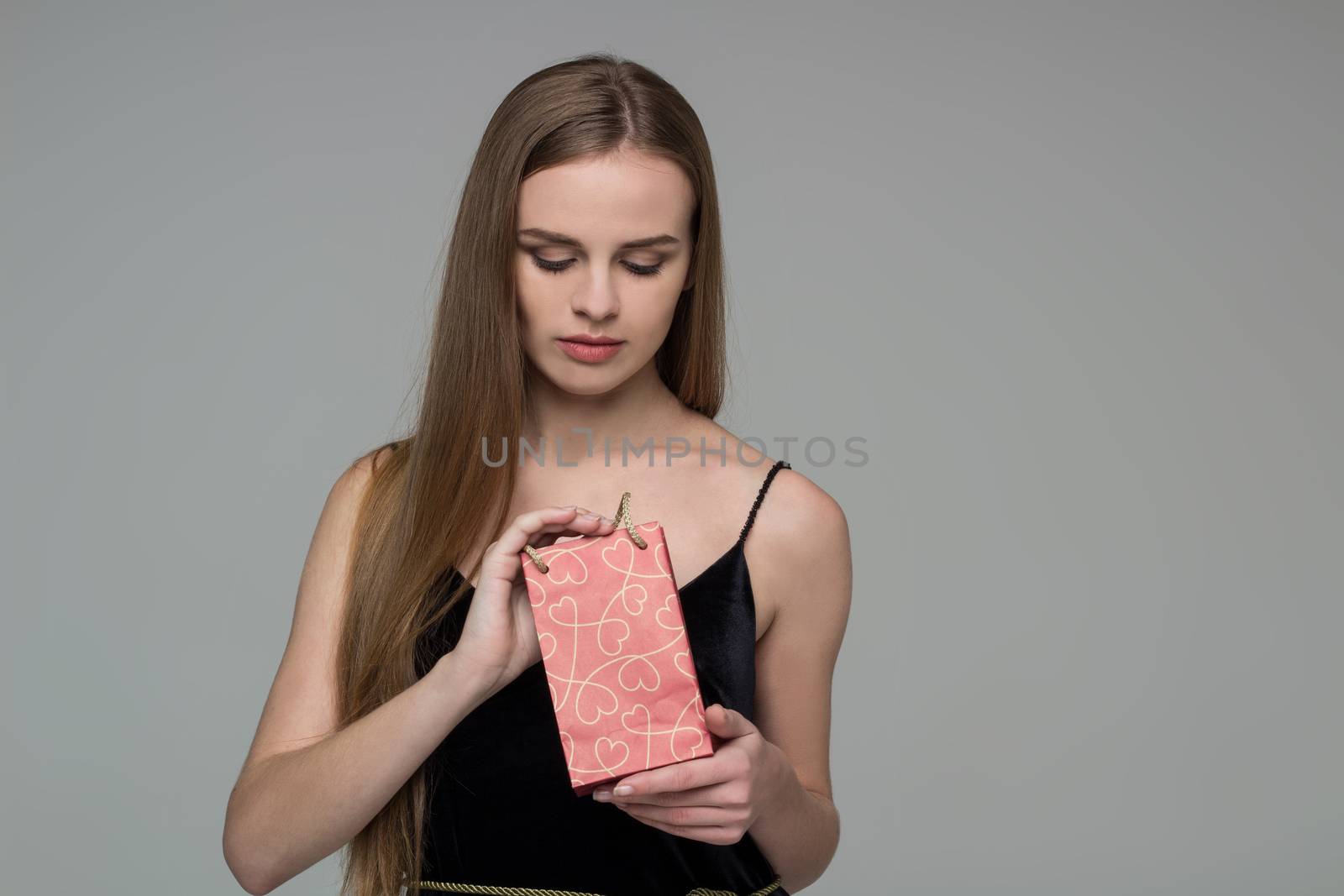 Young blond girl in black  dress with red gift bag by VeraVerano