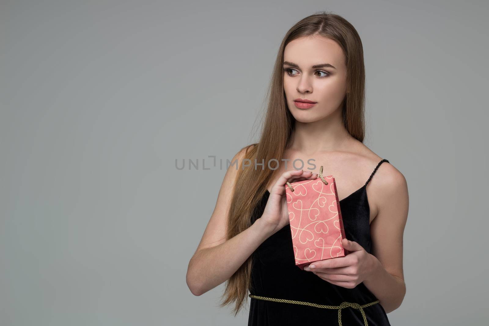 Young blond girl in black  dress with red present bag by VeraVerano