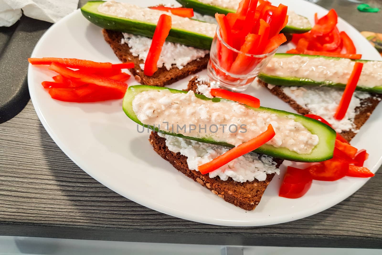 Cucumber cut in half with fresh quark and pepper strips stuffed on black bread. A low-calorie meal and vegan entree