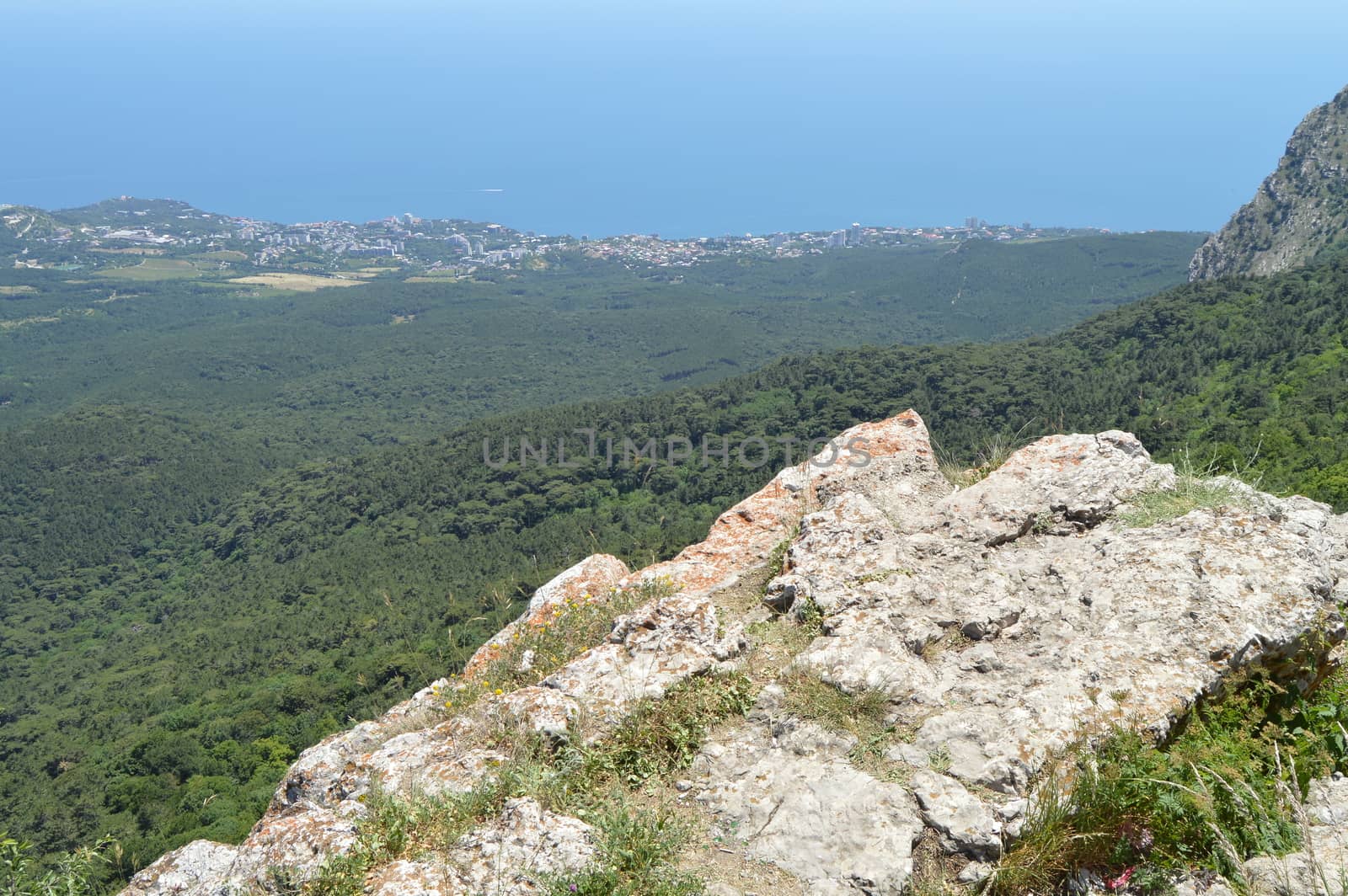 THE VIEW FROM THE ROCKY TOP OF THE MOUNTAIN TO THE PINE FOREST AND THE SEASIDE TOWN.