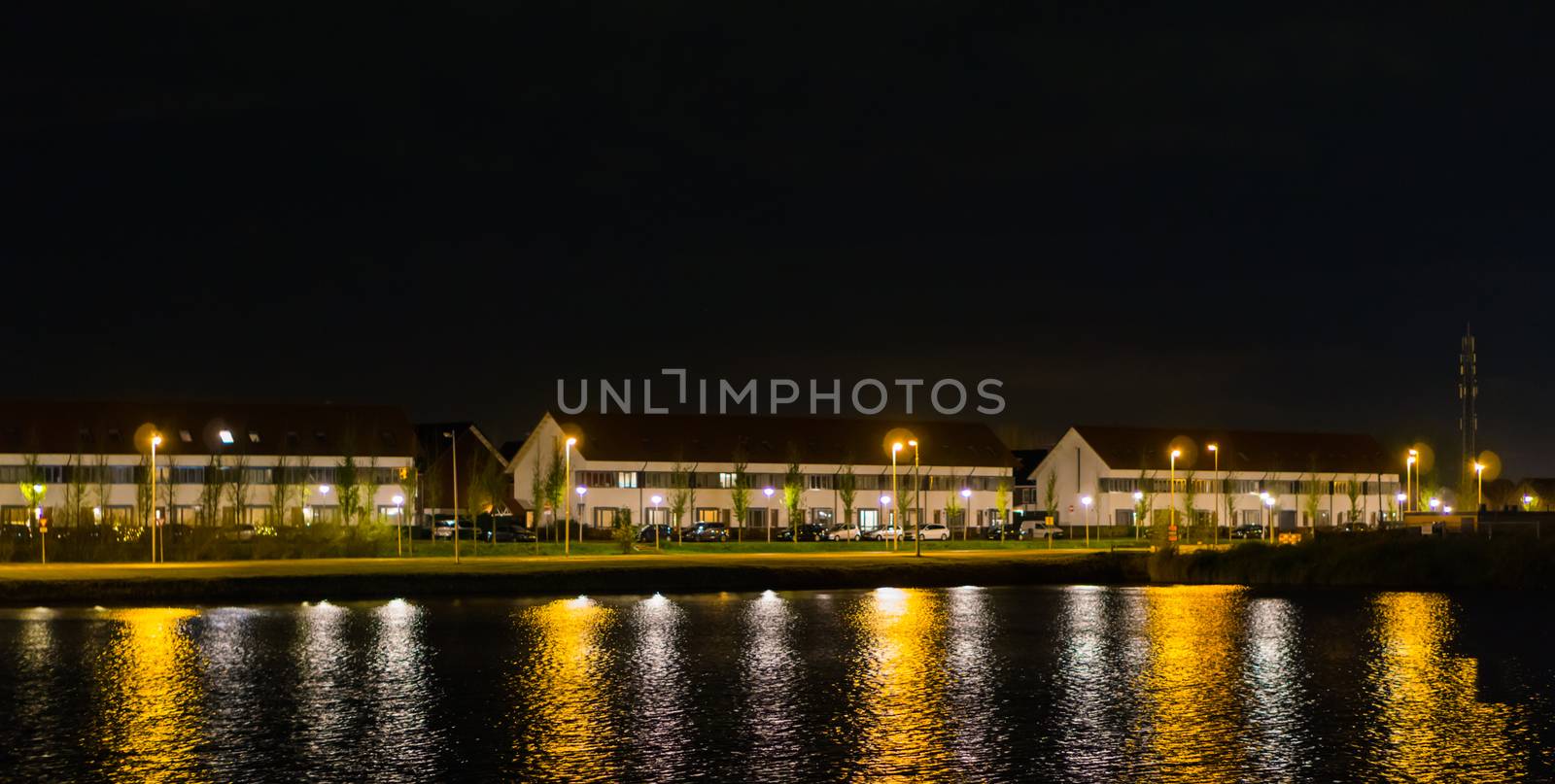 view from the water on houses and driving road at night time, dutch street view of landschapsbaan, the Meern, Utrecht the Netherlands by charlottebleijenberg