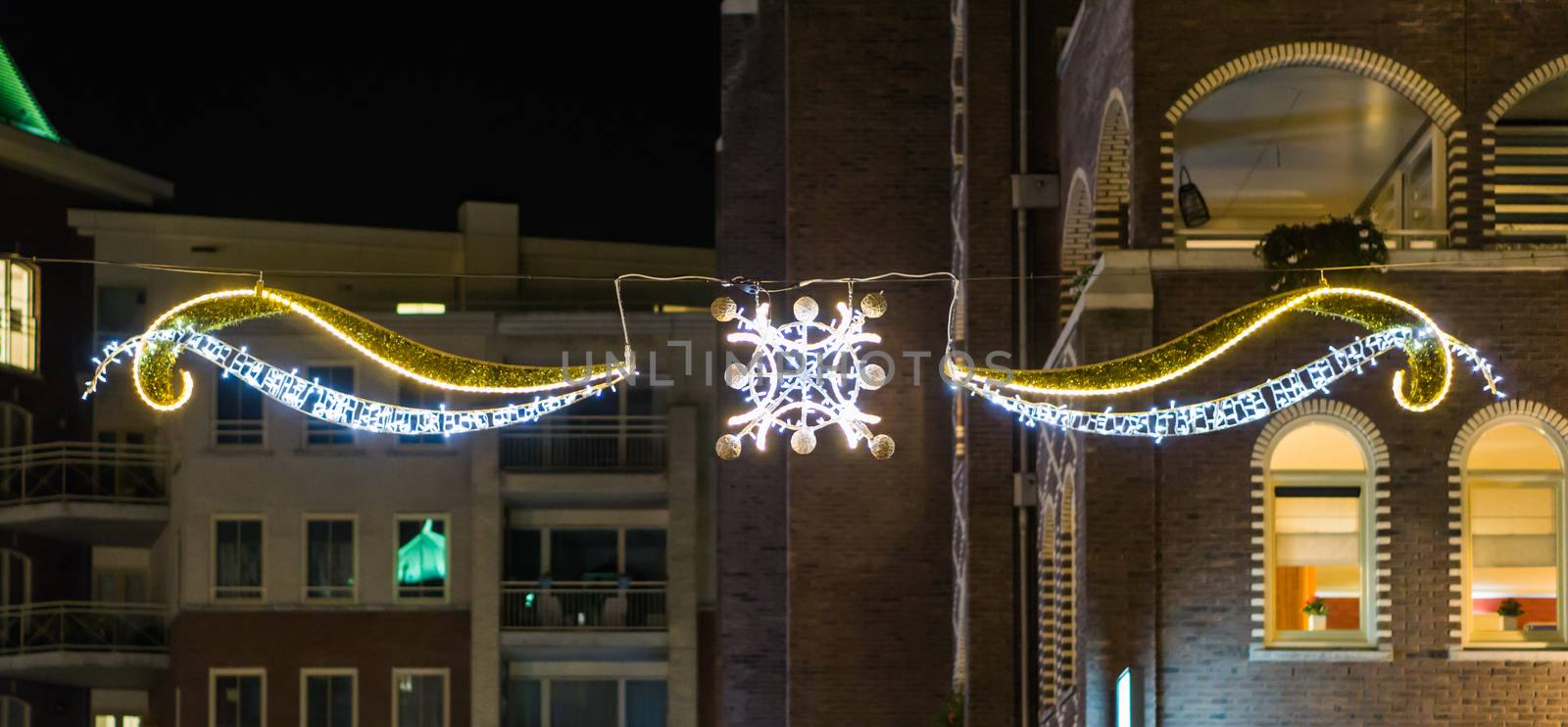 Beautiful christmas decoration with lights hanging between some buildings in the city streets at night time