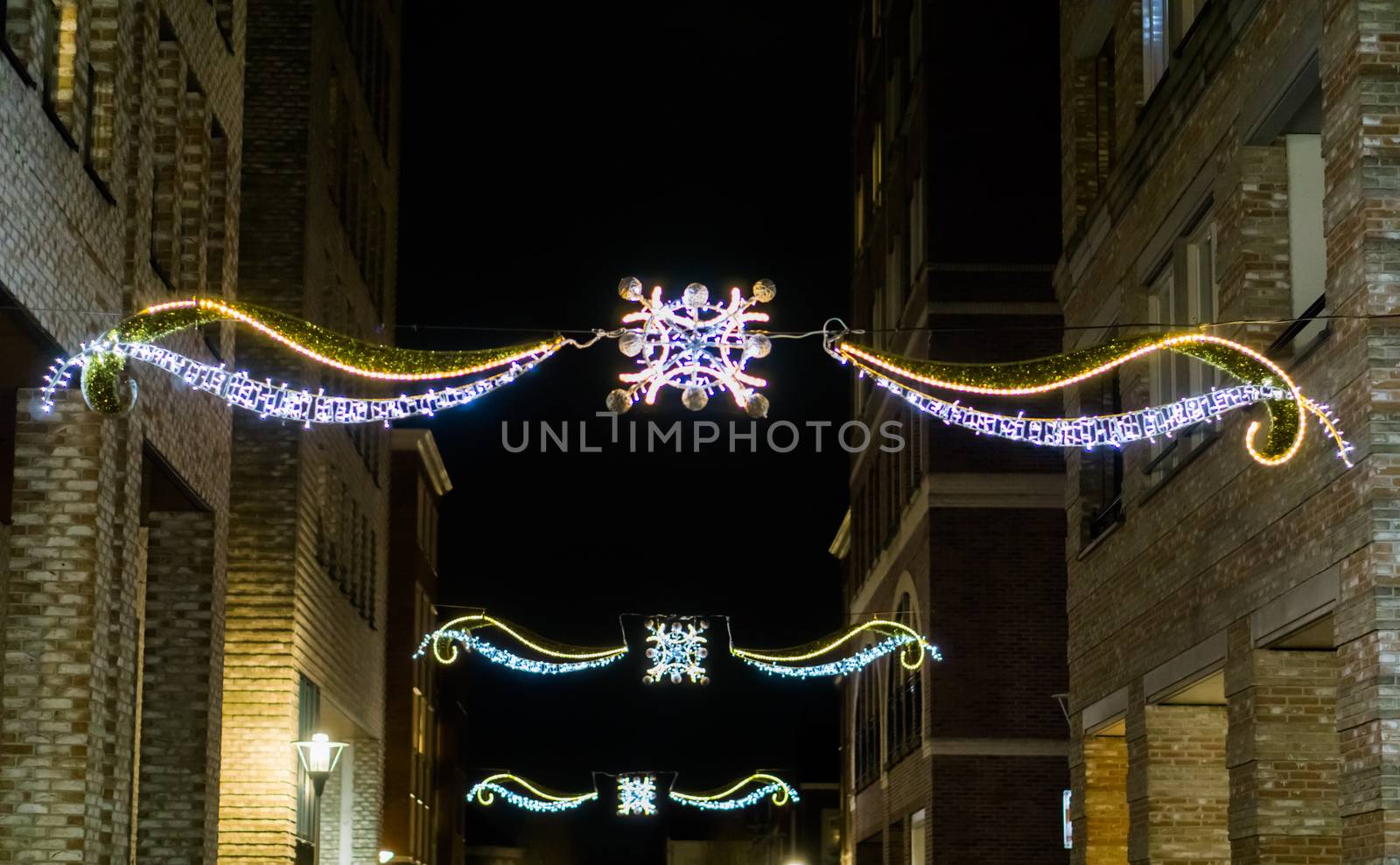 beautiful christmas decorations hanging between the buildings in the city streets at night by charlottebleijenberg