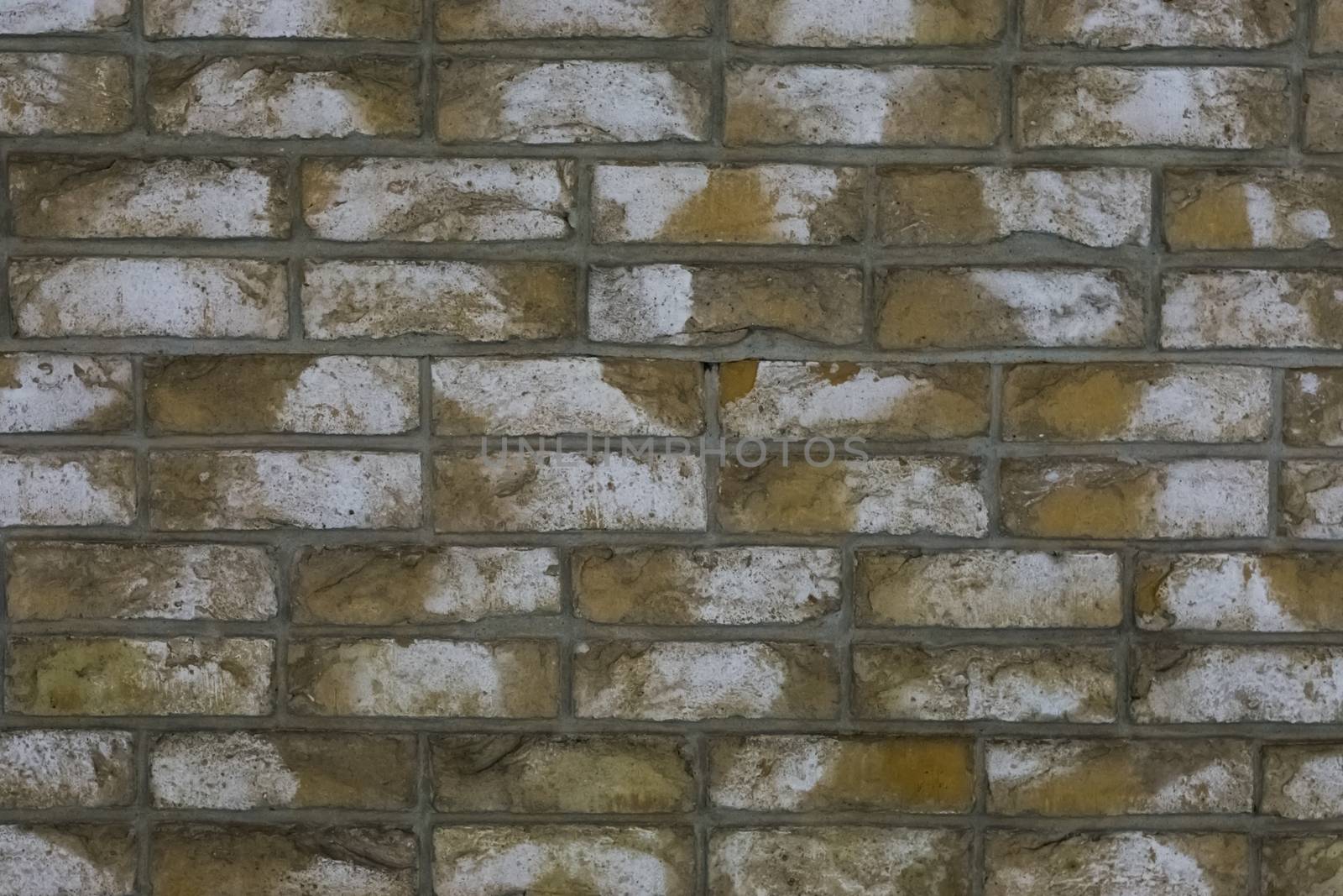 macro closeup of a yellow stone brick wall with white blotches, a architecture background.