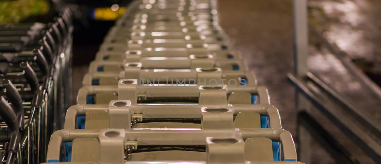 long row of supermarket shopping carts in closeup, a commercial supermarket background by charlottebleijenberg