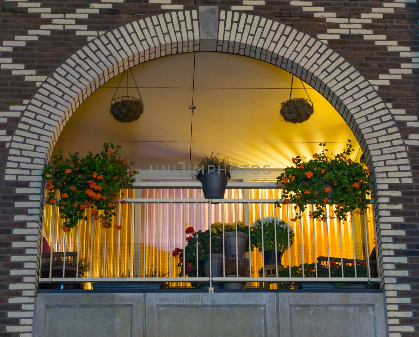 beautiful arched dutch balcony decorated with flowers at night, modern city buildings and architecture by charlottebleijenberg