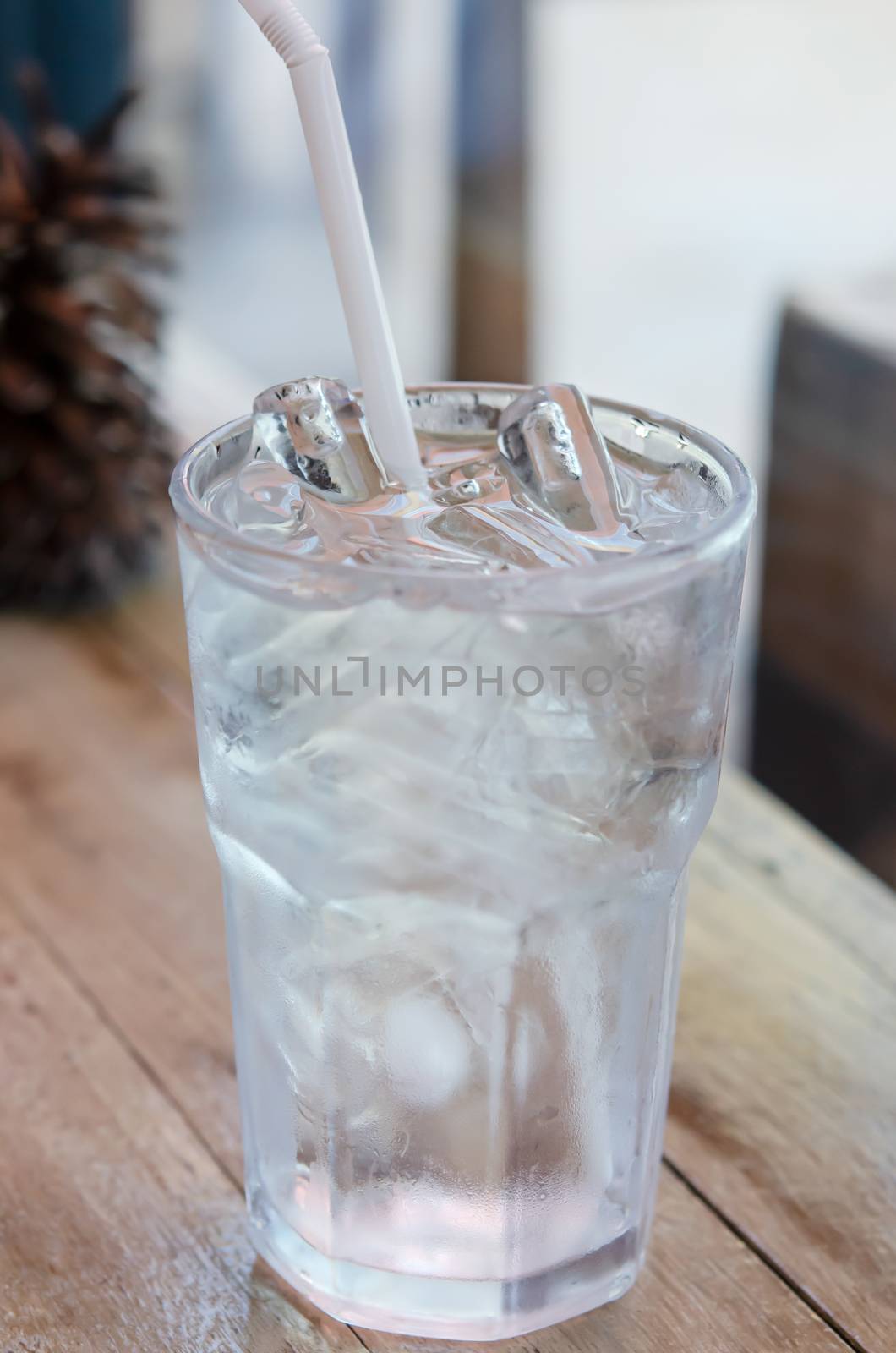 water in glass with ice  and drinking straw on table