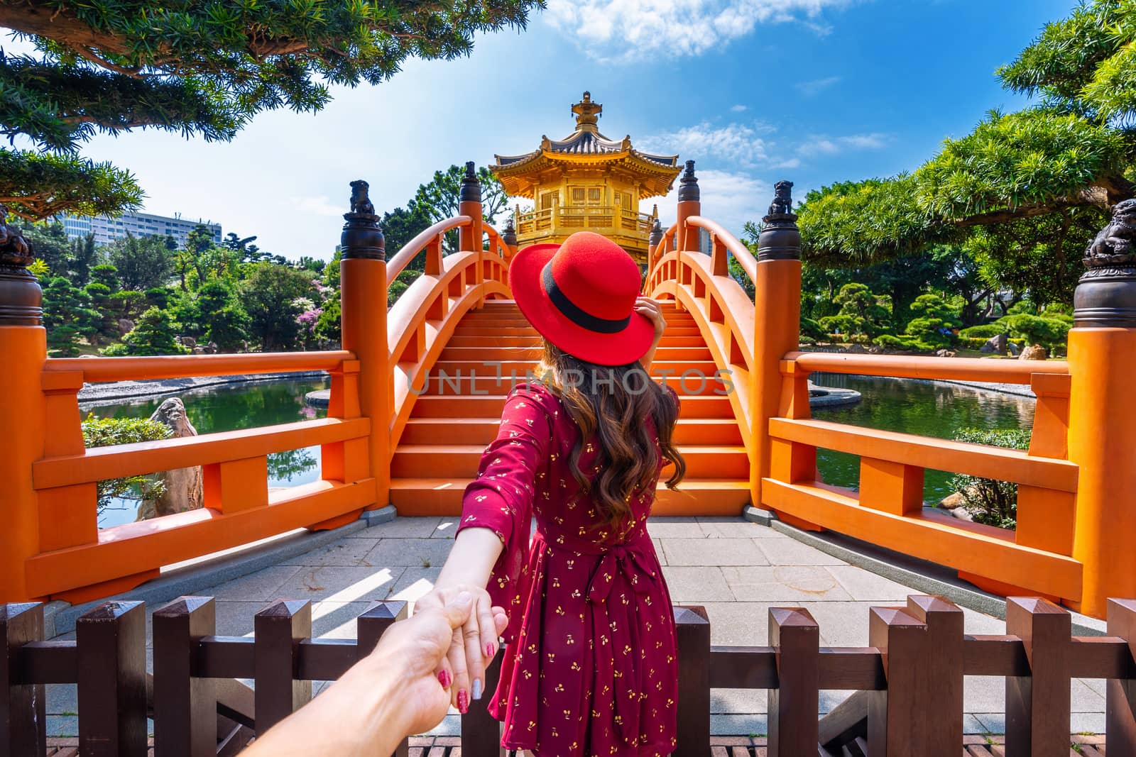 Women tourists holding man's hand and leading him to Golden Pavilion in Nan Lian Garden near Chi Lin Nunnery temple, Hong Kong. by gutarphotoghaphy
