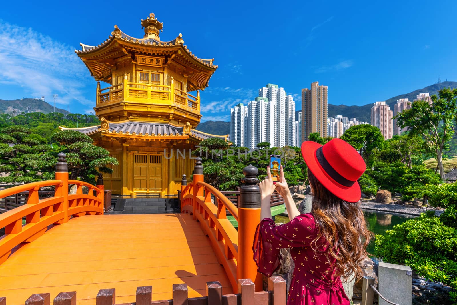 Woman take a photo at Golden Pavilion in Nan Lian Garden near Chi Lin Nunnery temple, Hong Kong. by gutarphotoghaphy