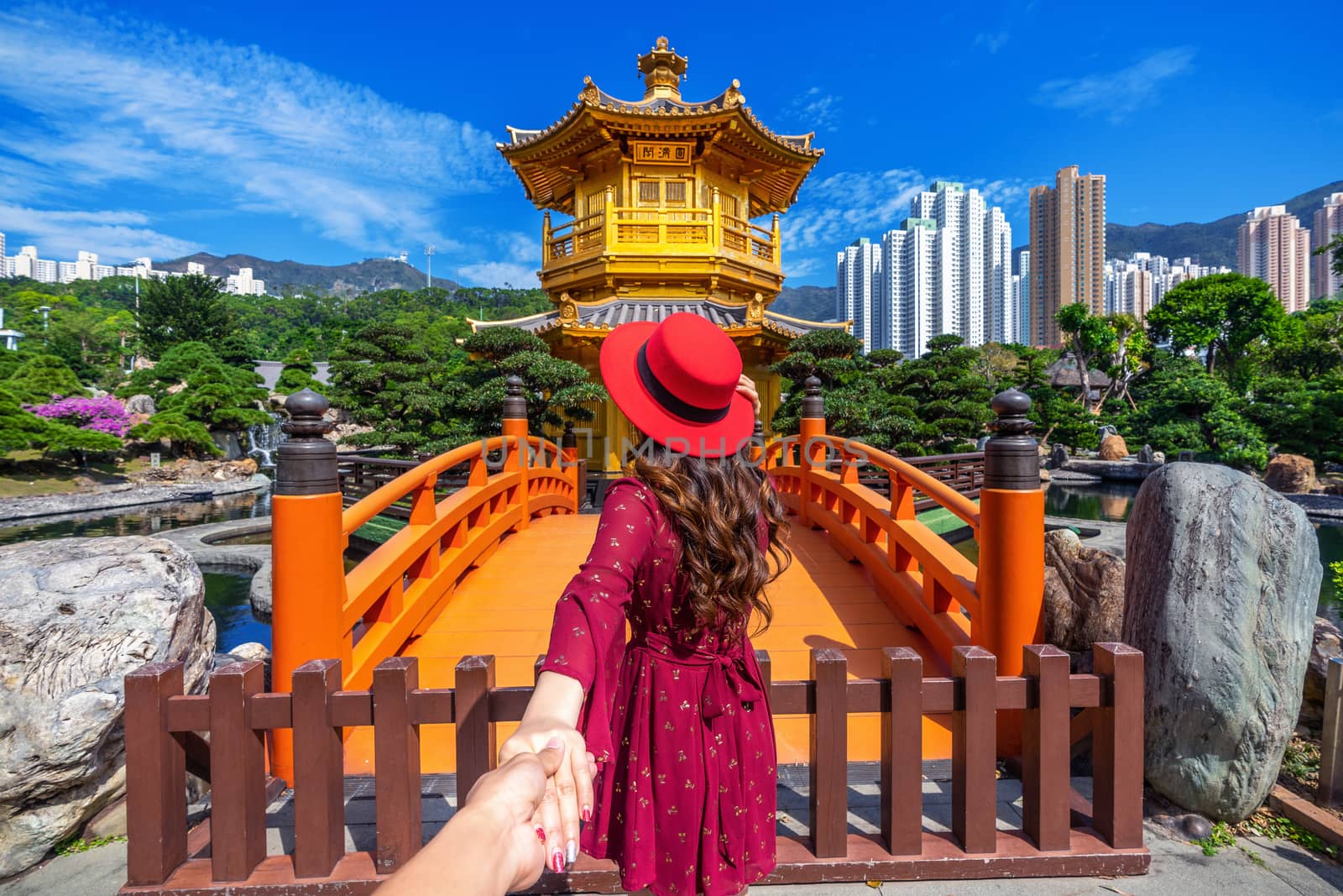 Women tourists holding man's hand and leading him to Golden Pavilion in Nan Lian Garden near Chi Lin Nunnery temple, Hong Kong.