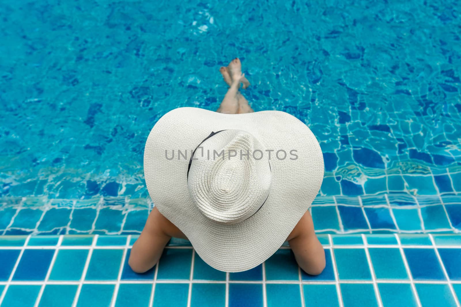 Asian woman relaxing in swimming pool. by gutarphotoghaphy