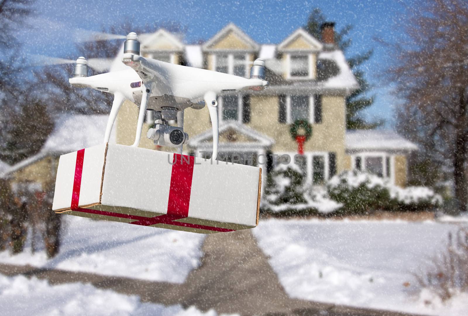 Unmanned Aircraft System (UAV) Quadcopter Drone Delivering Box With Red Ribbon To Home by Feverpitched
