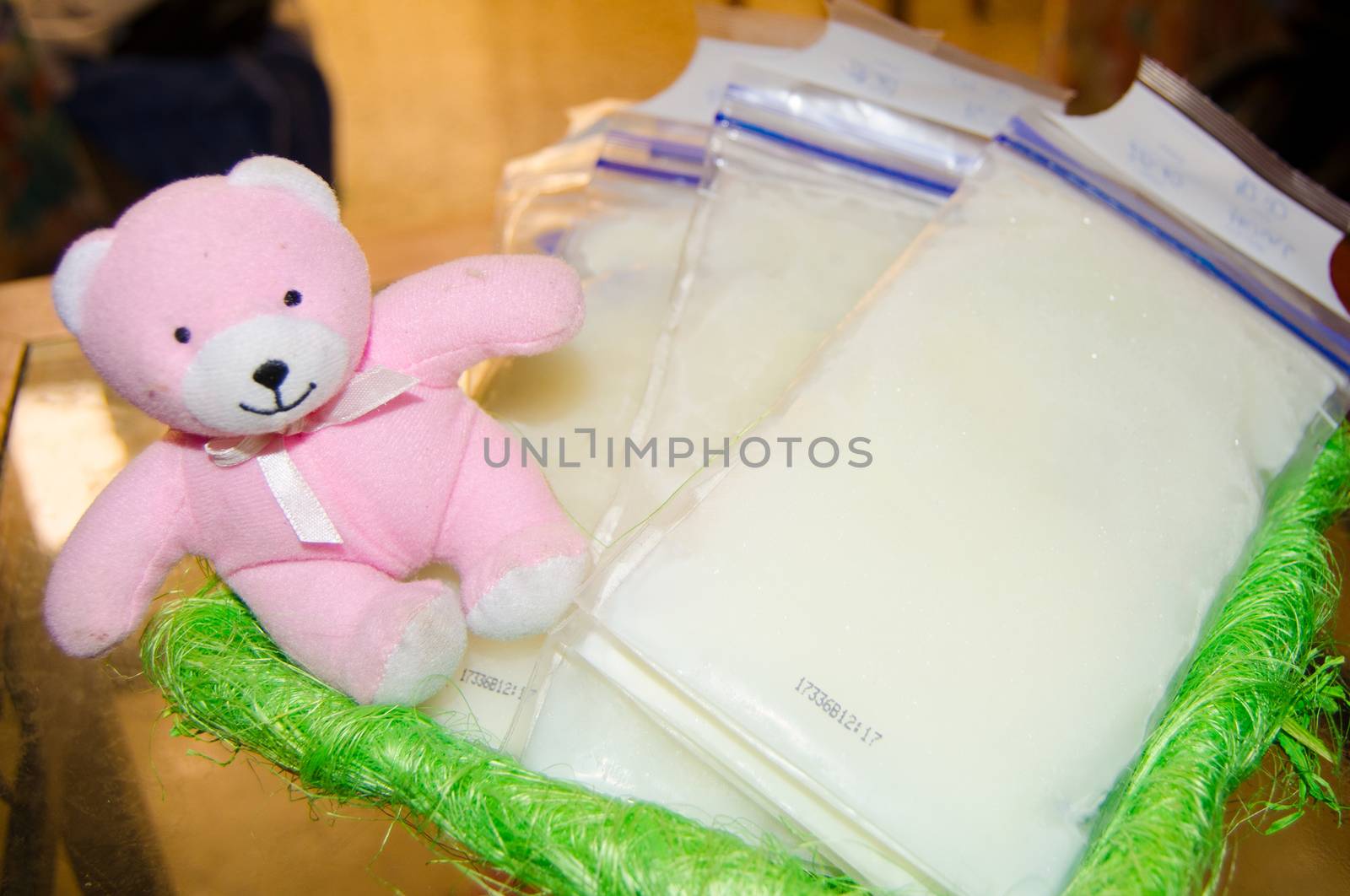 frozen breast milk in storage bags in the basket, with soft toy pink teddy bear by negmardesign