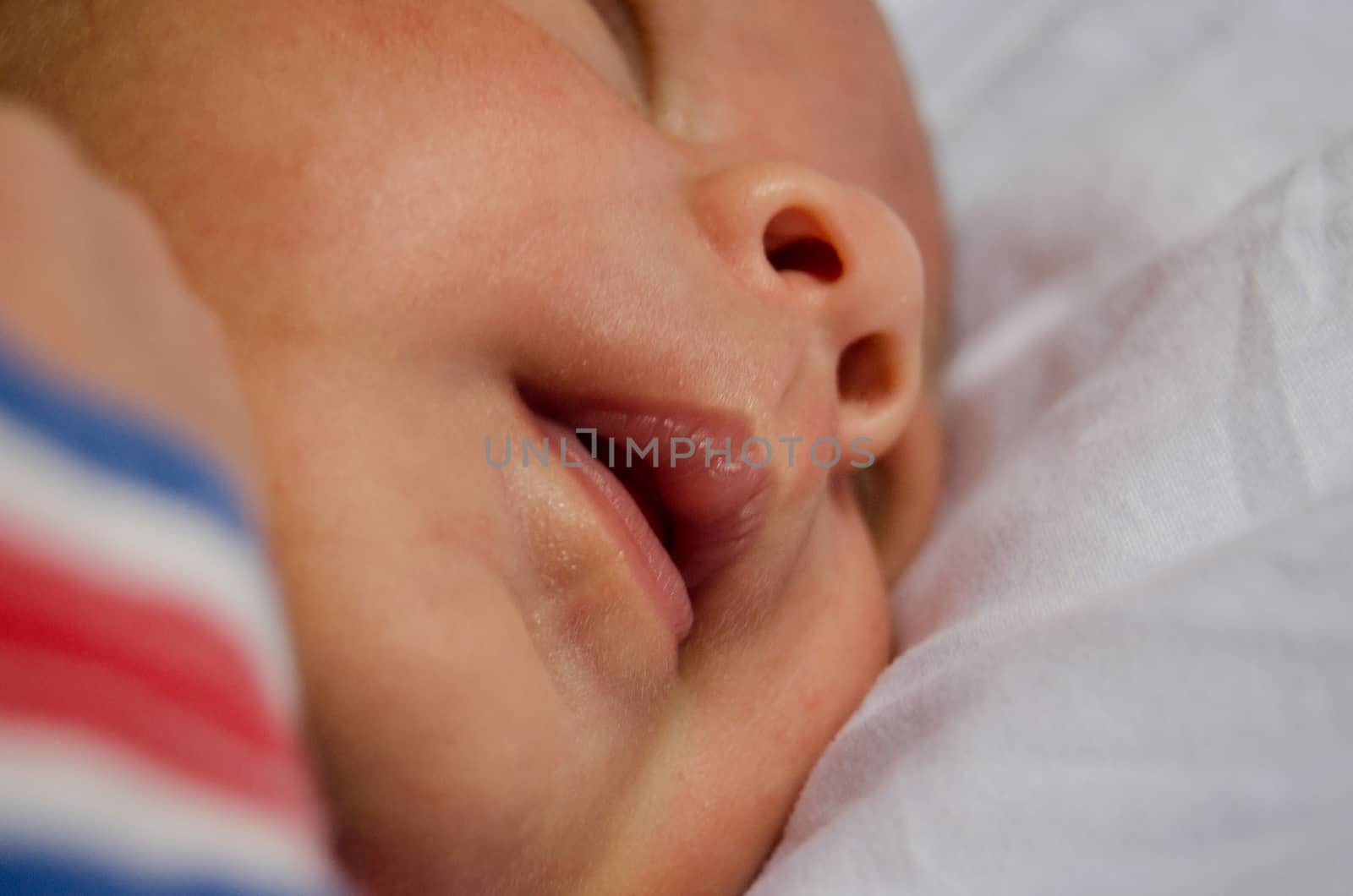 little baby boy focus on his mouth, sleeping on white quilt