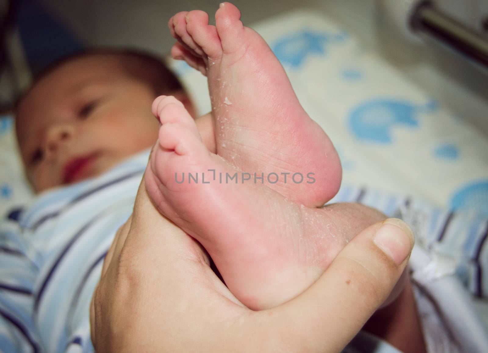 Mother massaging little newborn baby foot relaxing by negmardesign